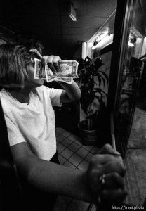 Girl locking the door of Electric Beach, a tanning studio, and covering her face with money. (this was to test the new TMAX 3200 film, rated at 6400 ASA and mostly shot with a 15mm lens.)