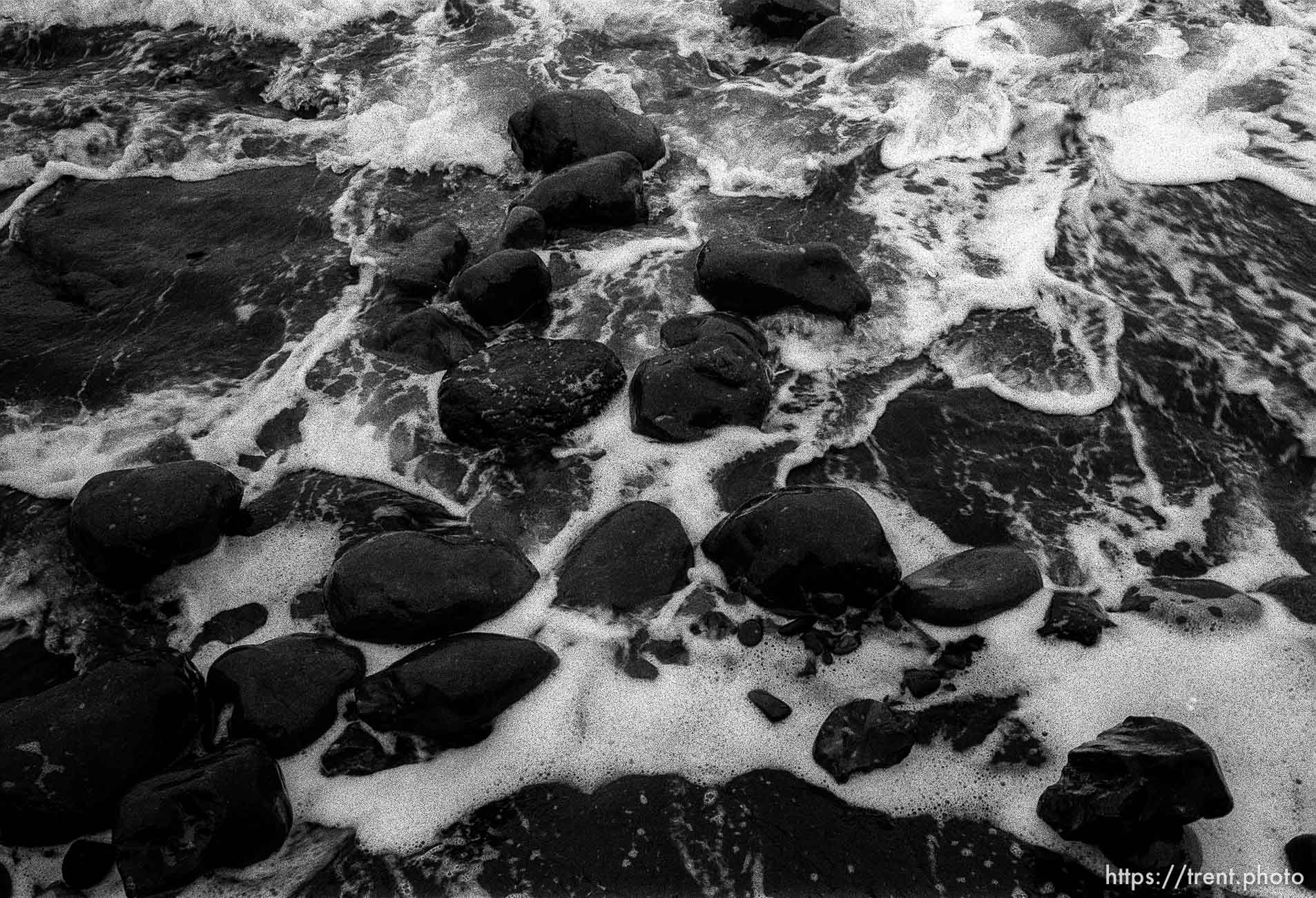 black rocks and surf at beach.