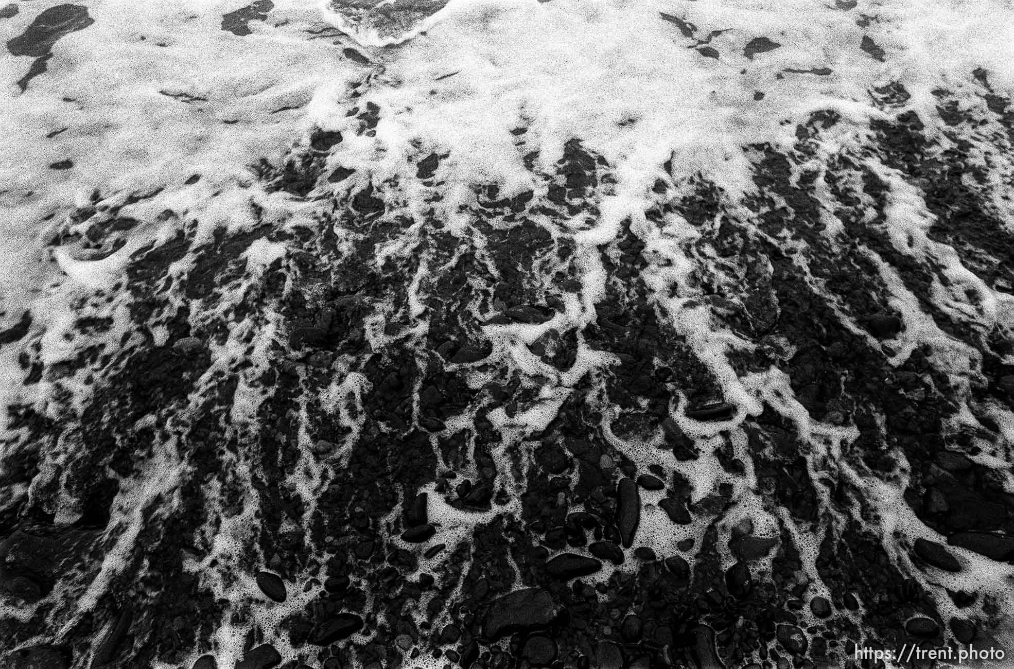 Black rocks and surf at the beach.