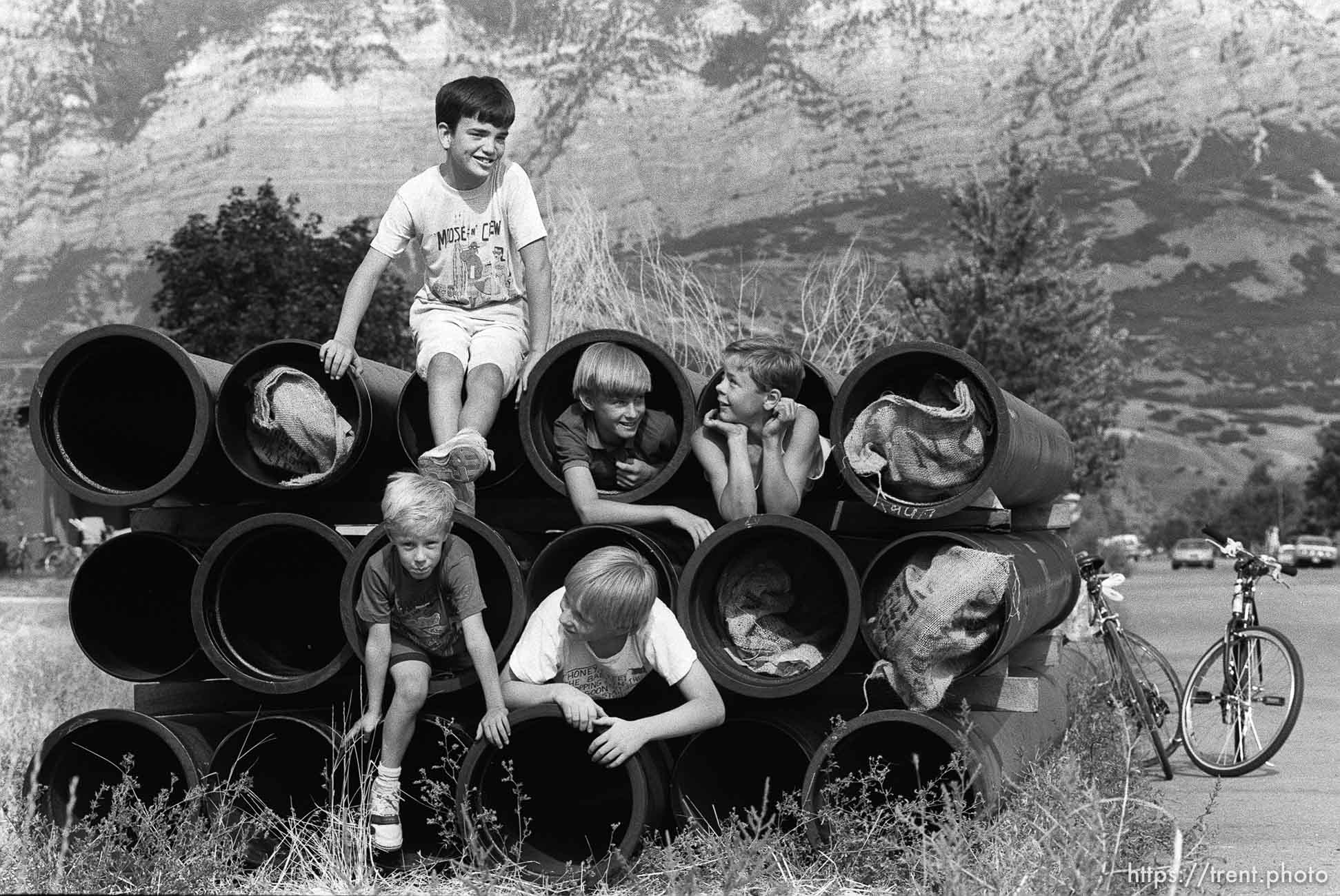 Kids playing on stack of pipes.