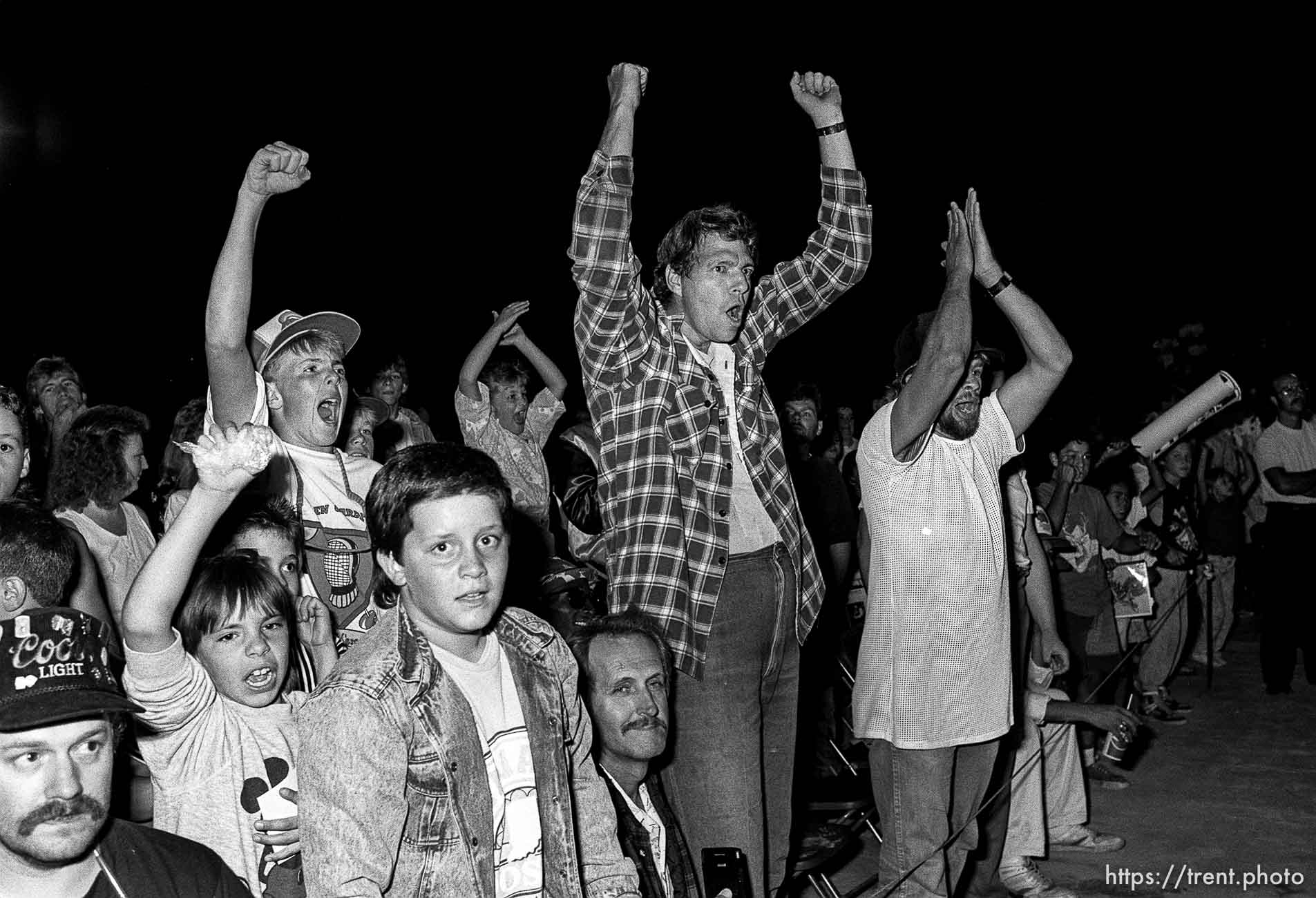 Crowd cheers at professional wrestling match.