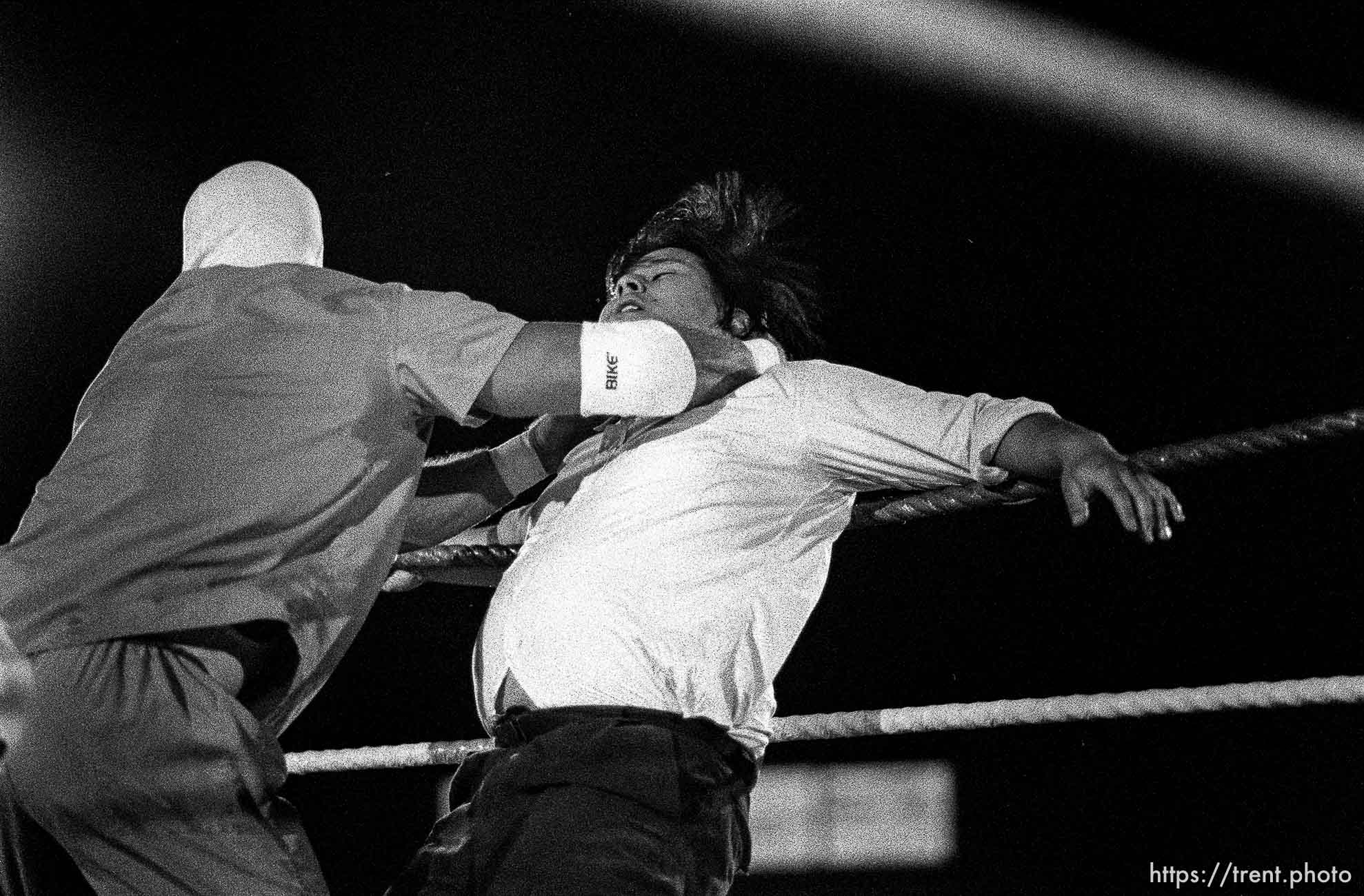 Heel wreslter chokes the referee at professional wrestling match.