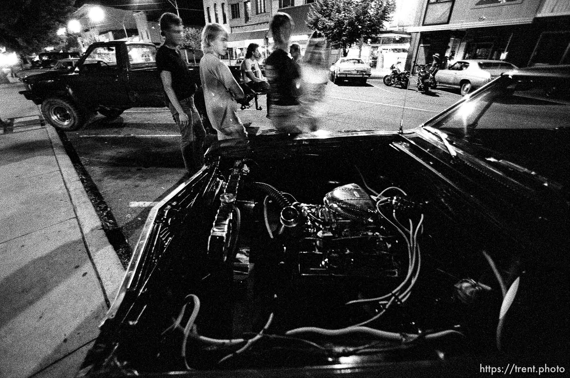 Kids checking out a muscle car on Center Street at night.