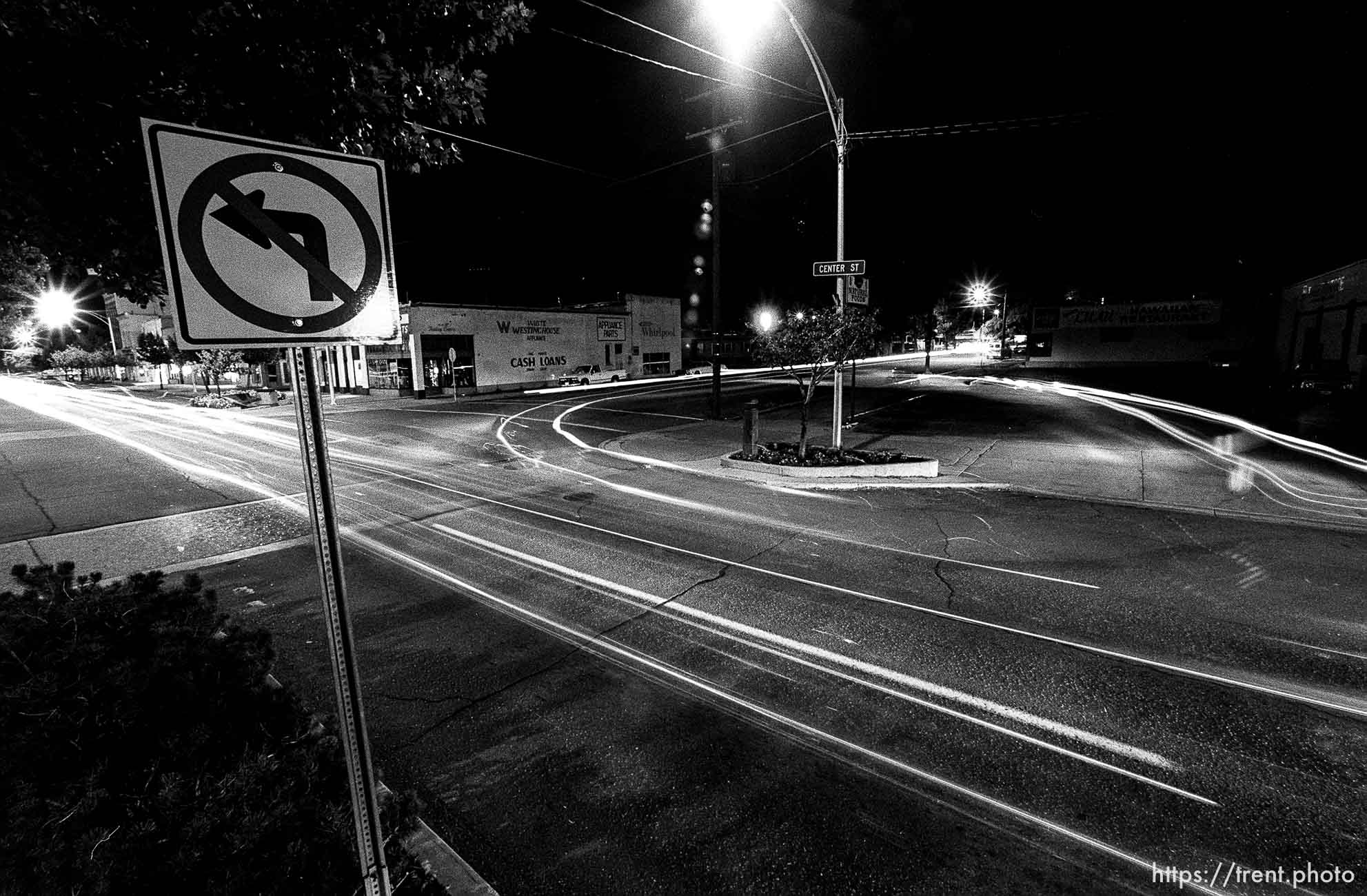 Cars U-turn to cruise on Center Street at night.