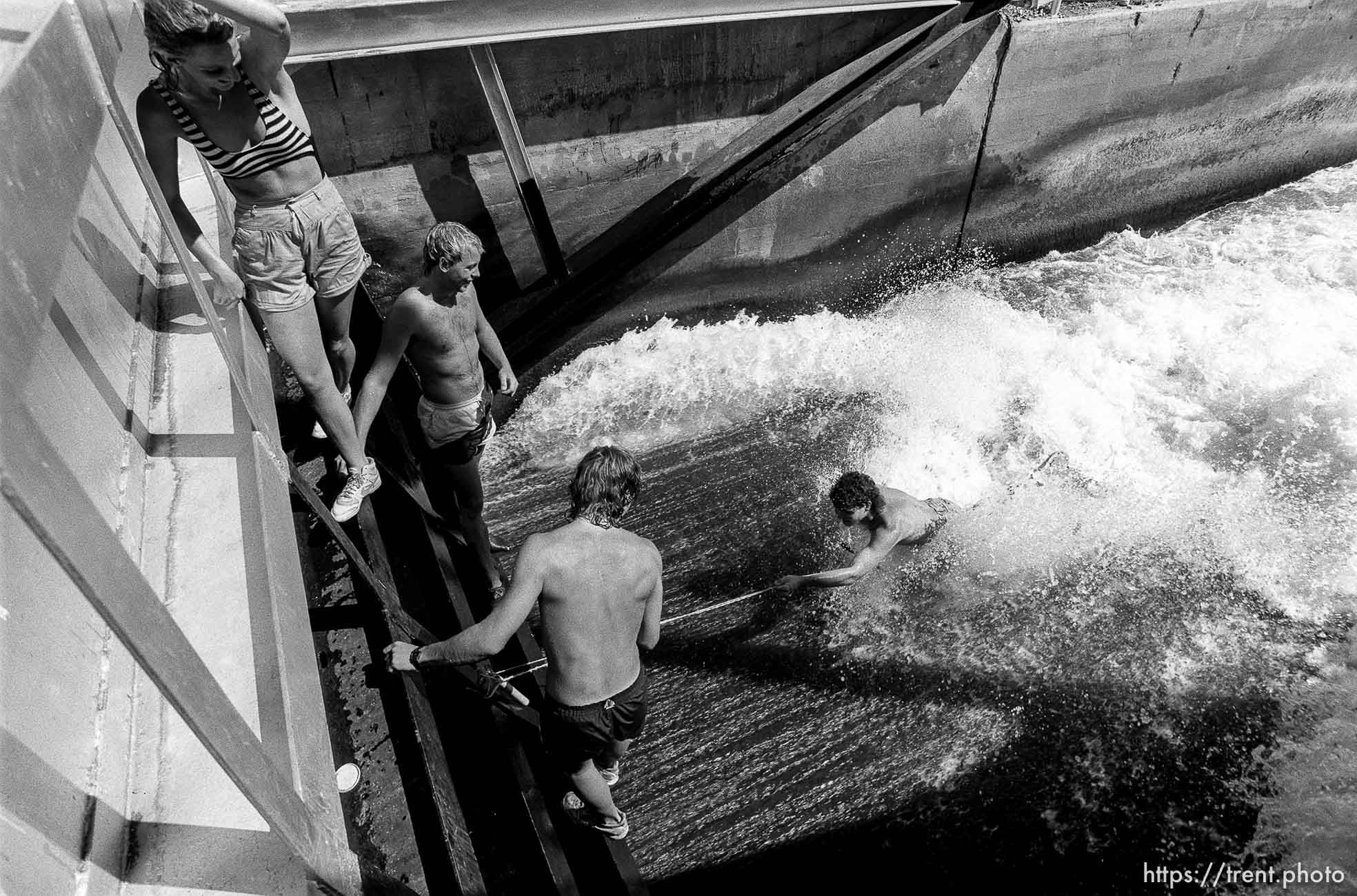 Guy surfing in water spillway.