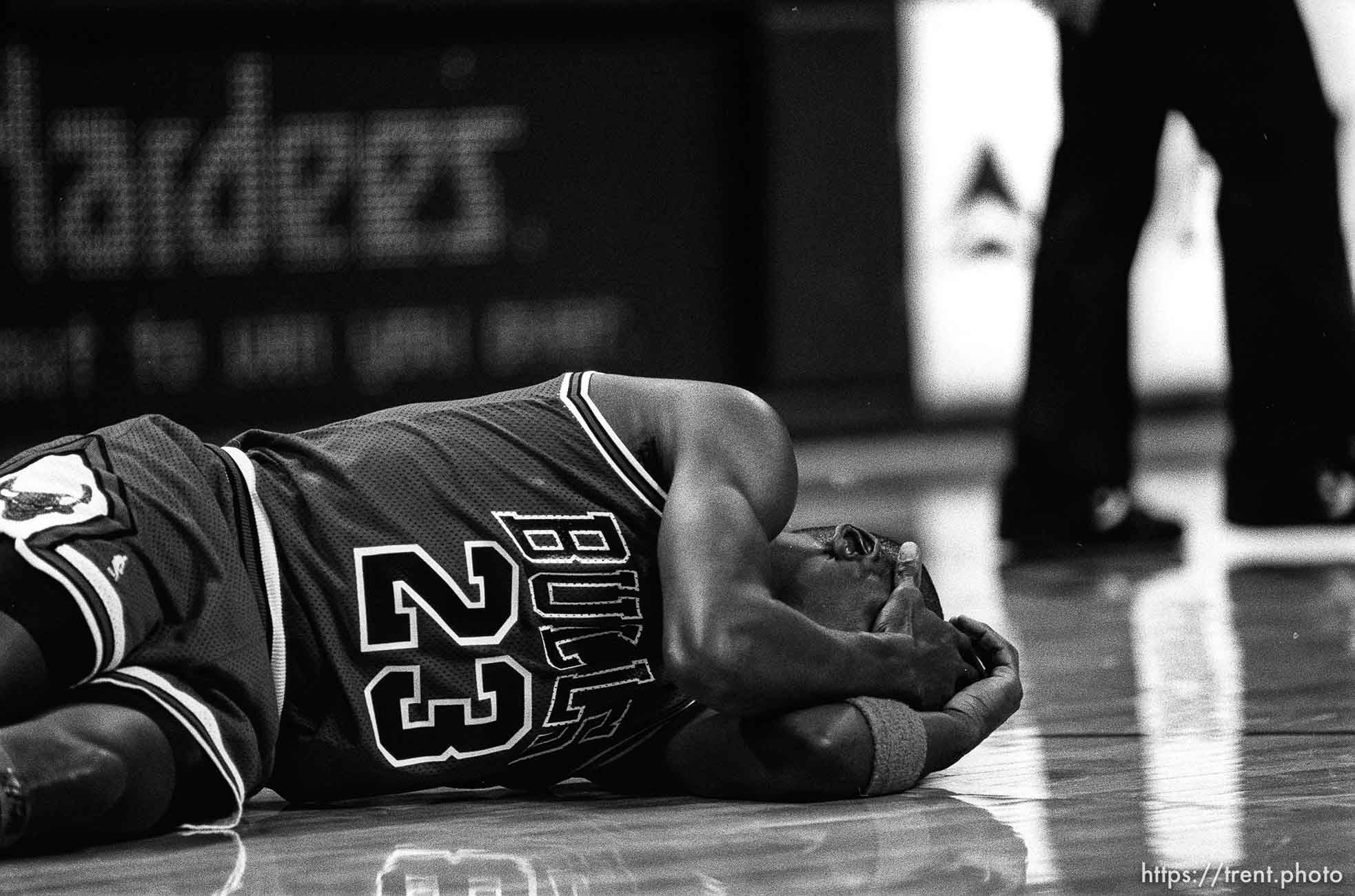 Michael Jordan  on the ground holding his head at Jazz vs. Chicago basketball.