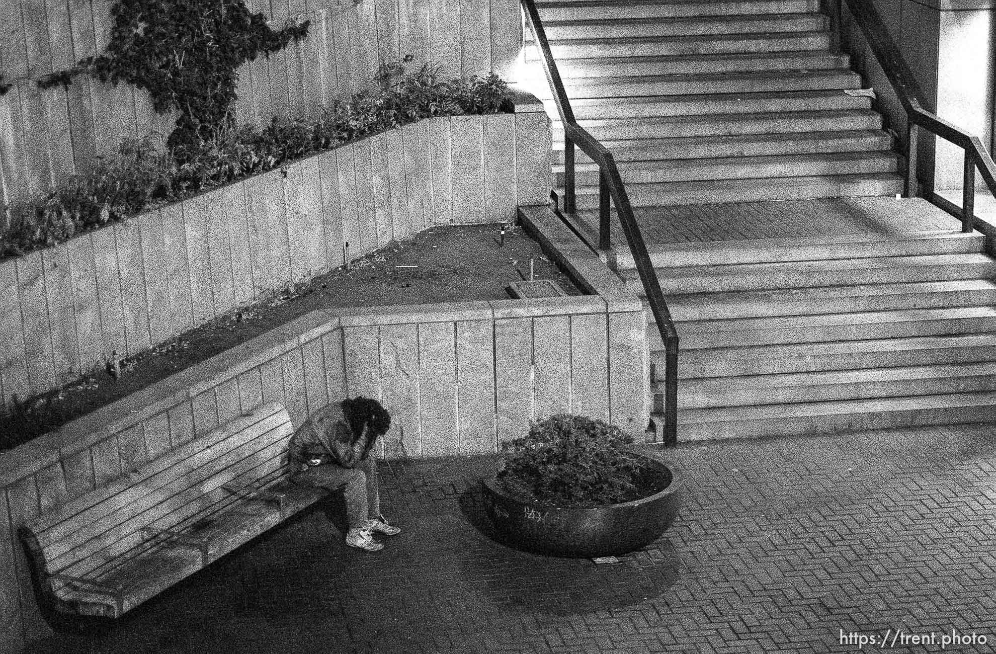 Person with their head in their hands on Market Street at night.