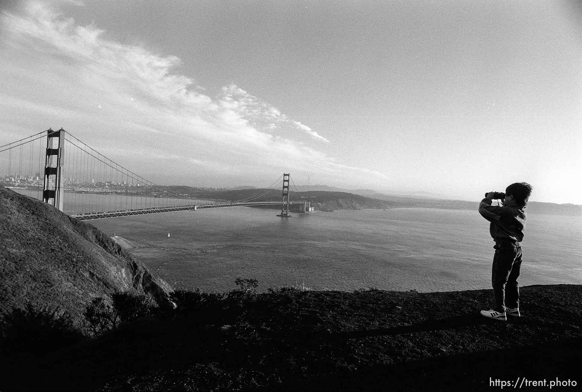 Kid with binoculars and view of Golden Gate Bridge and San Francisco.