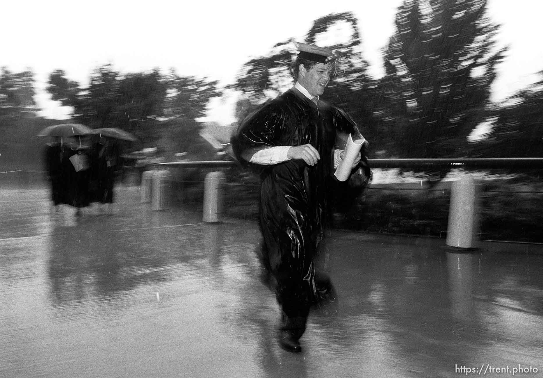 BYU graduates running to their graduation in the pouring rain.