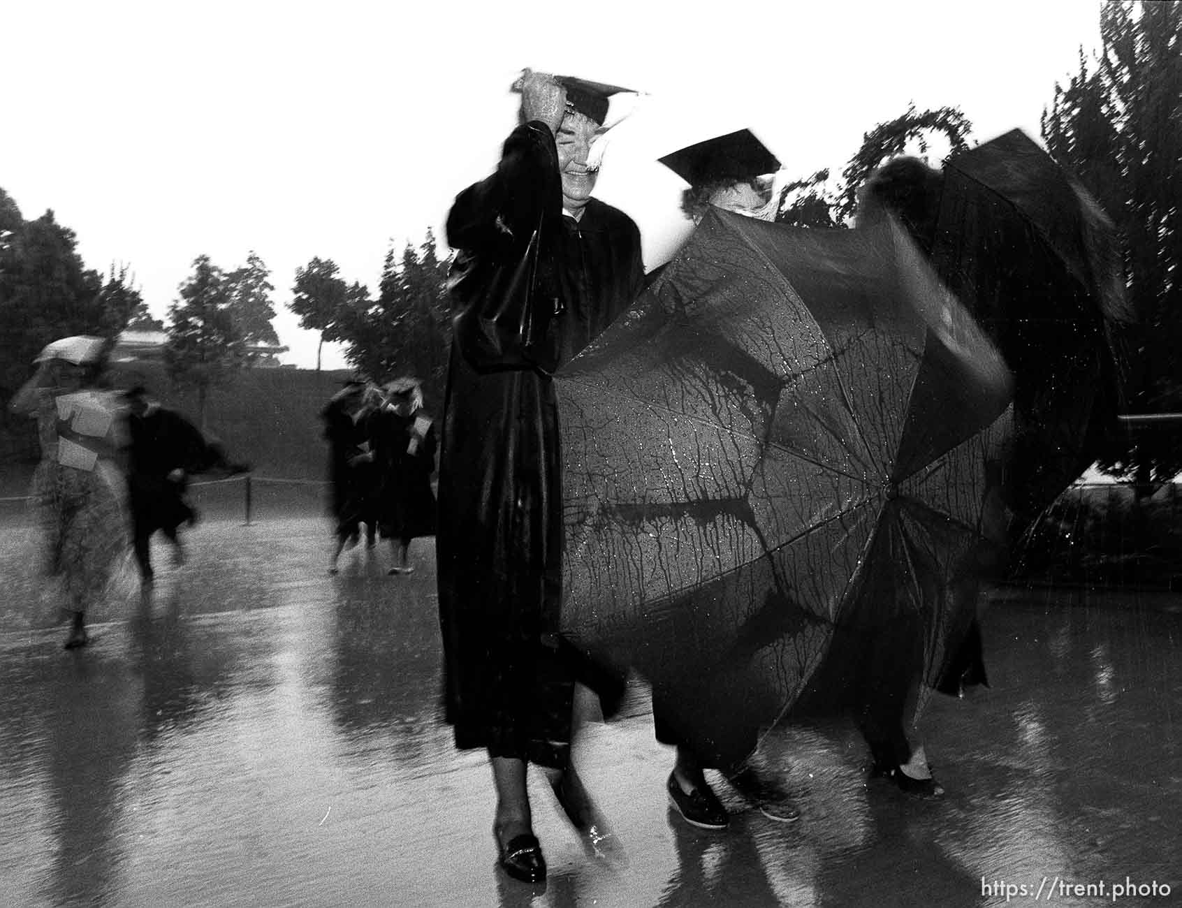 BYU graduates running to their graduation in the pouring rain.