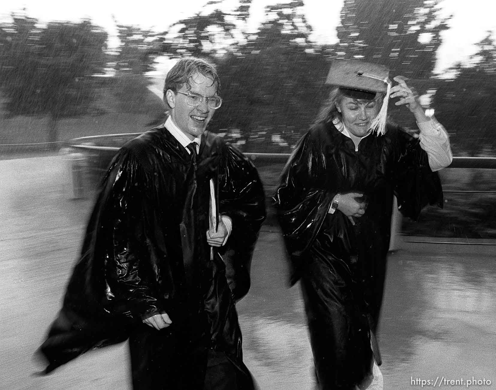 BYU graduates running to their graduation in the pouring rain.