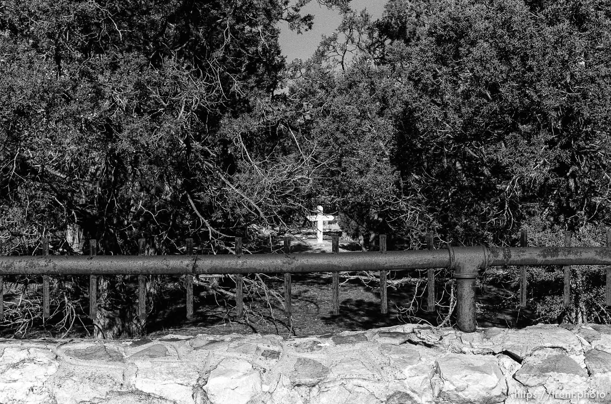 White cross and wall at secret graveyard.