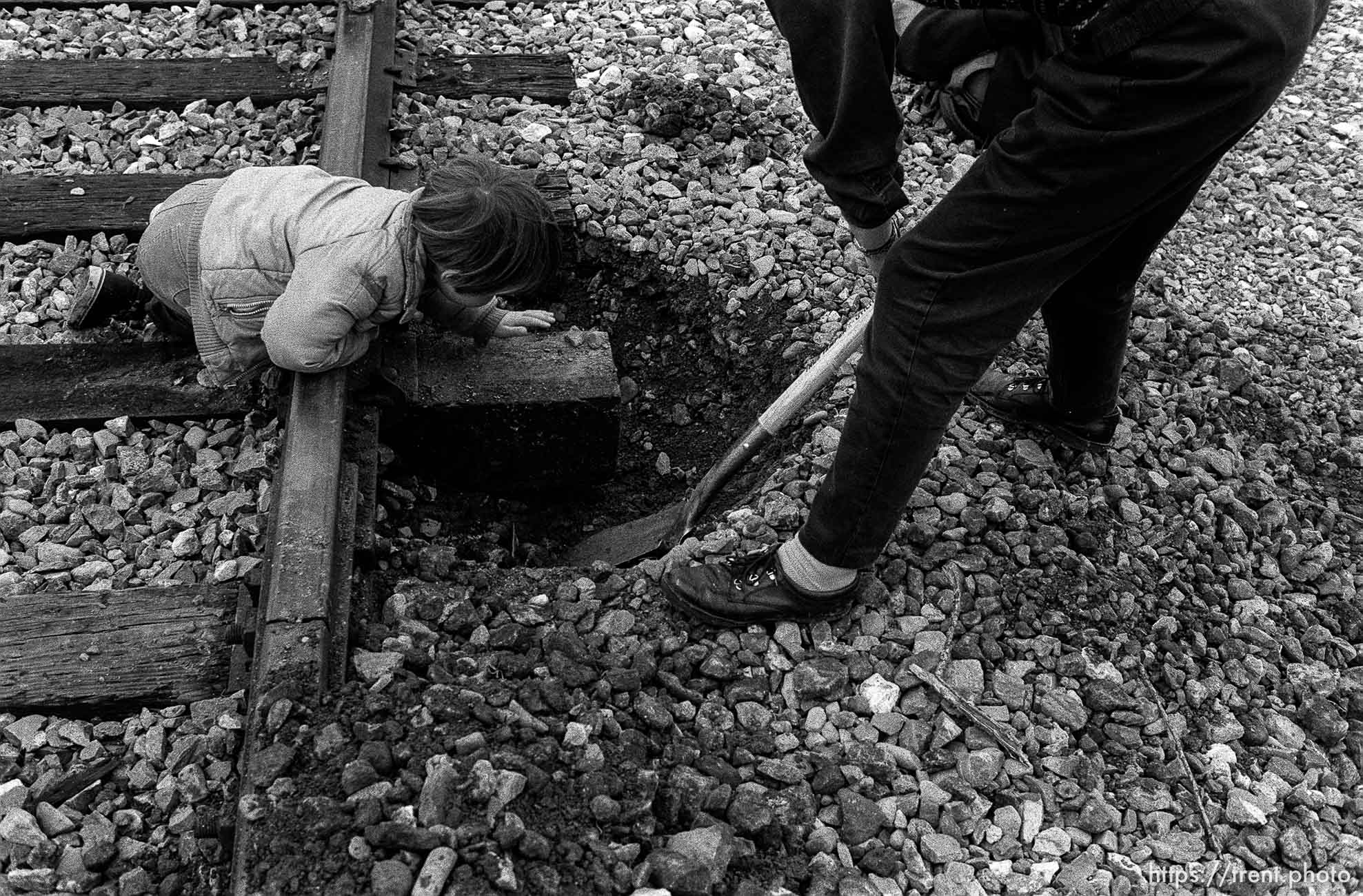 Woman digs up train tracks with a shovel while young child looks on at Gulf War protest at the Concord Naval Weapons Station.