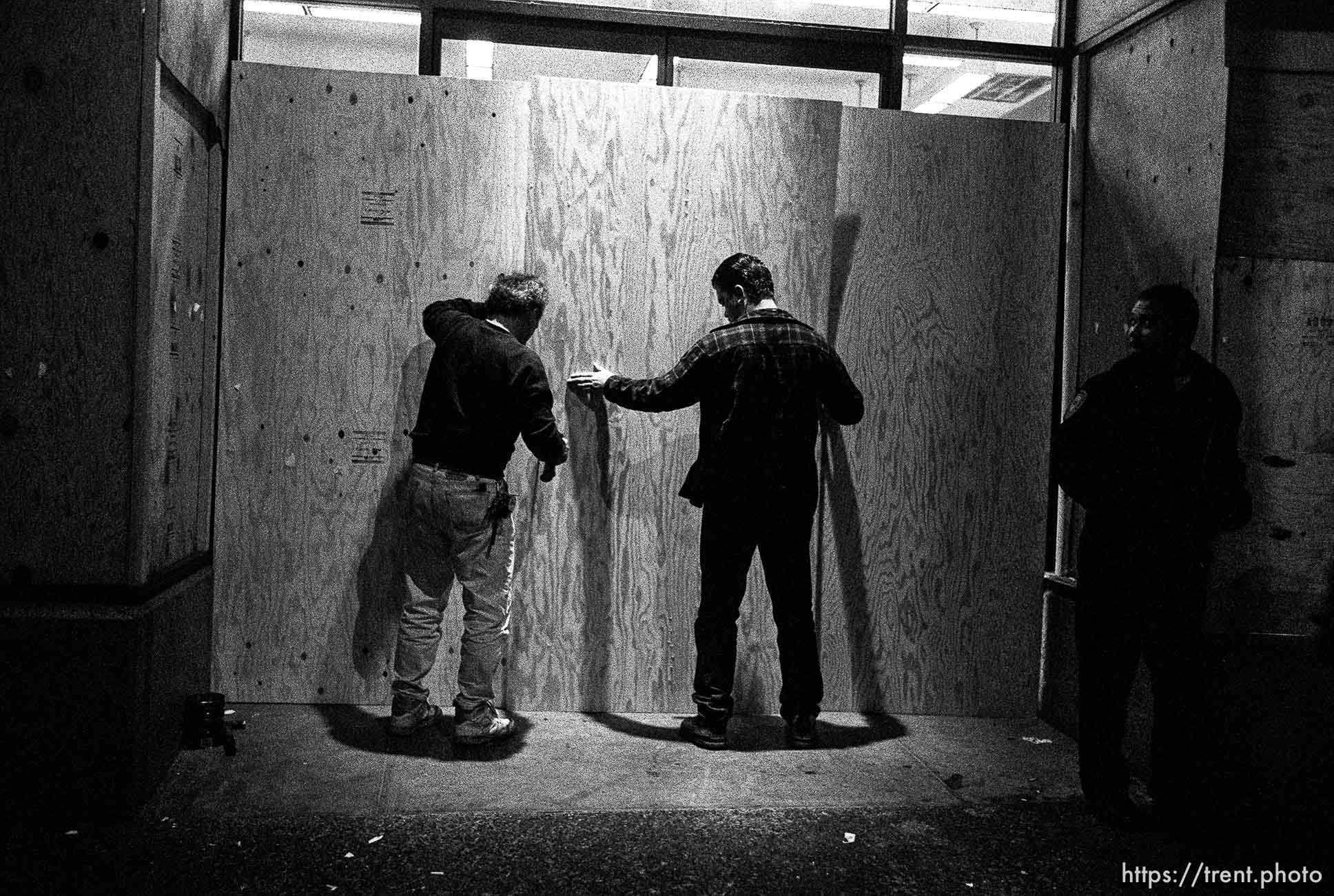 Men board up windows after riots along Telegraph Avenue.