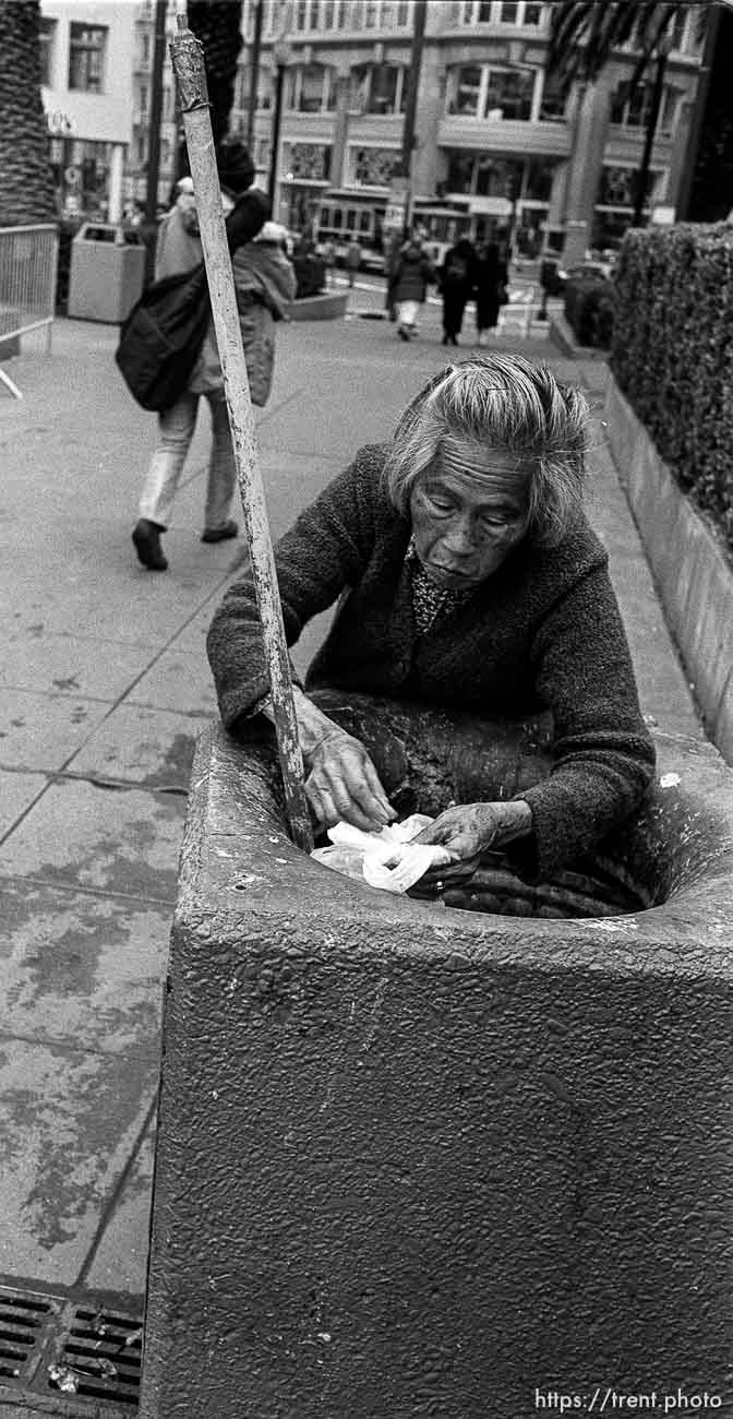 Woman picks through trash can