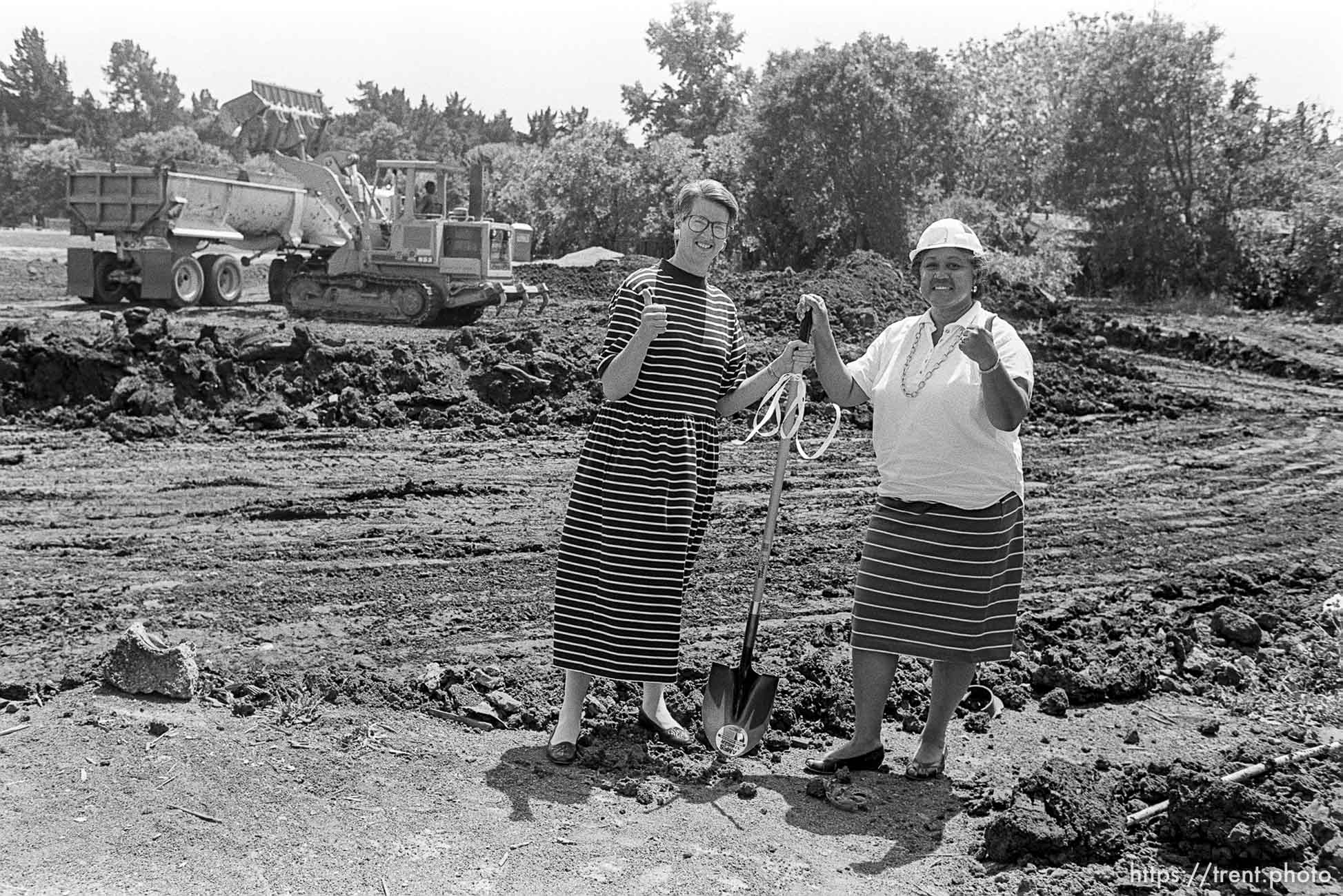 Women in a field with a shovel, giving the thumbs-up sign