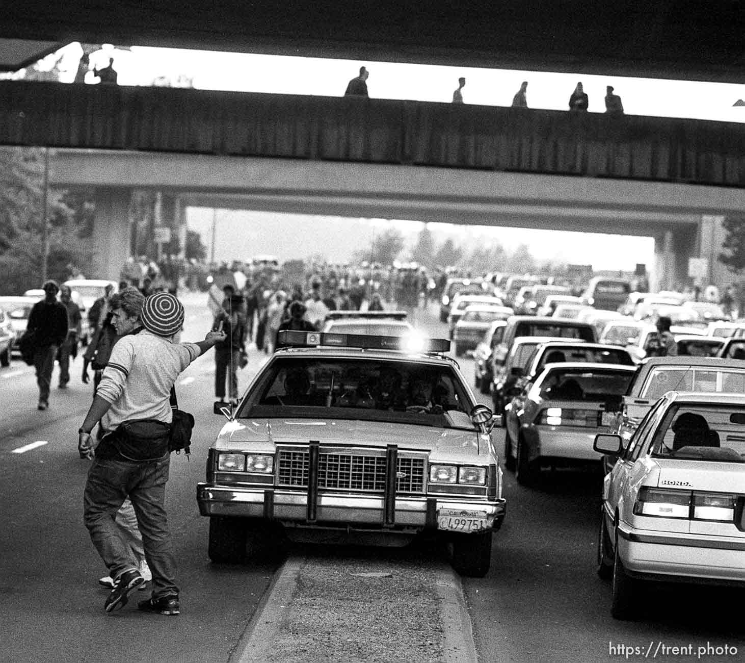 Man flips off police car during protests over President George Bush's visit to town.