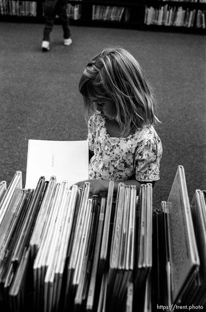 Girl in library looking at books at first day of kindergarten