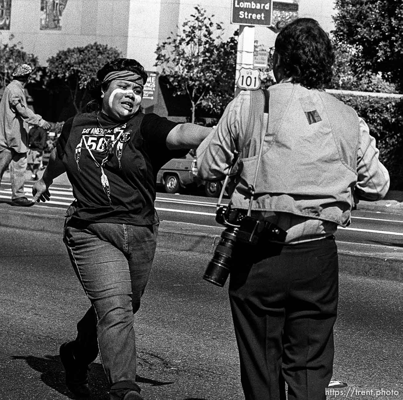 American Indian Movement woman grabs for Paul Sakuma's cameras at anti-Christopher Columbus protest.