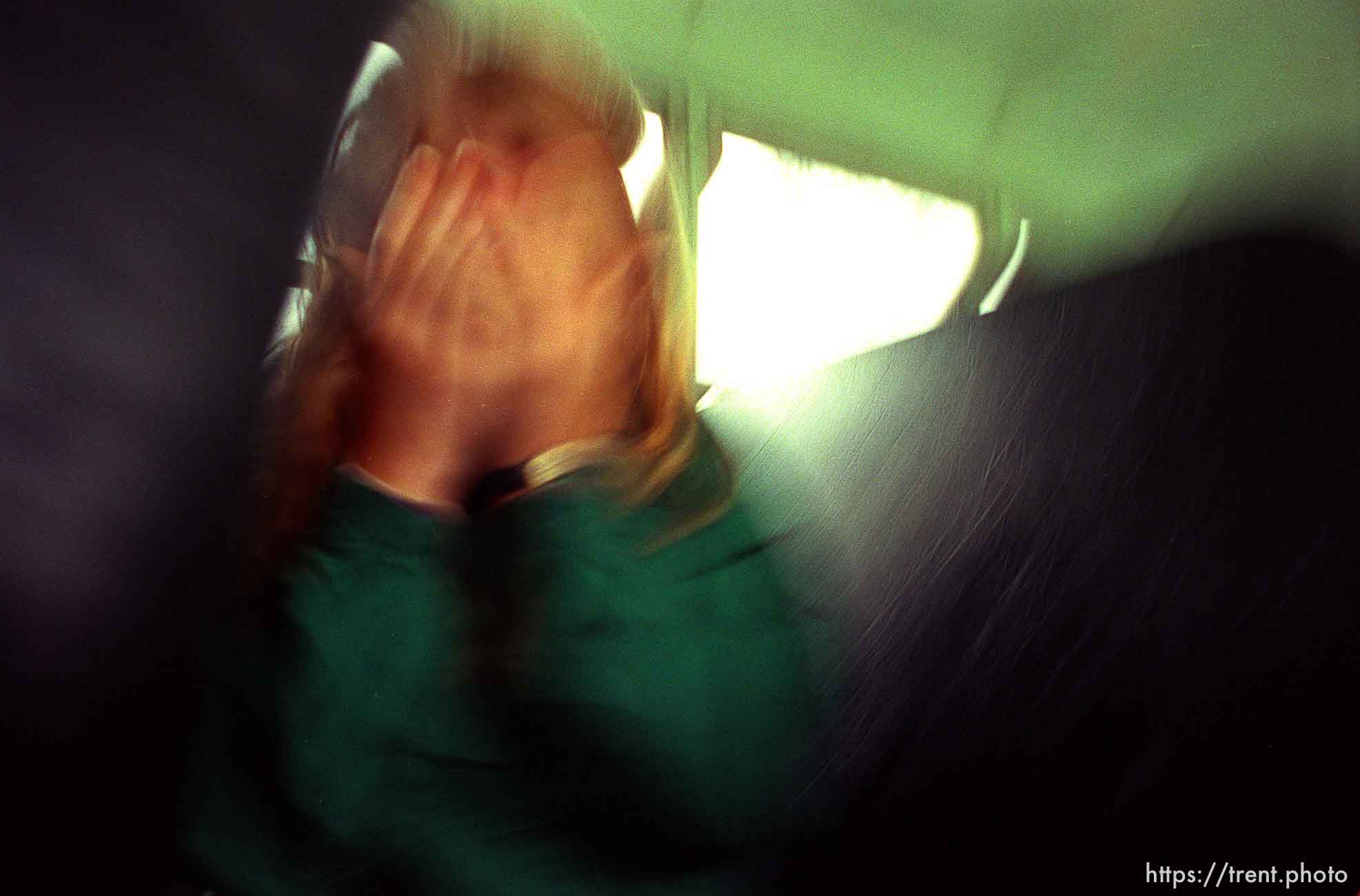 Girl covering her face from camera on school bus.