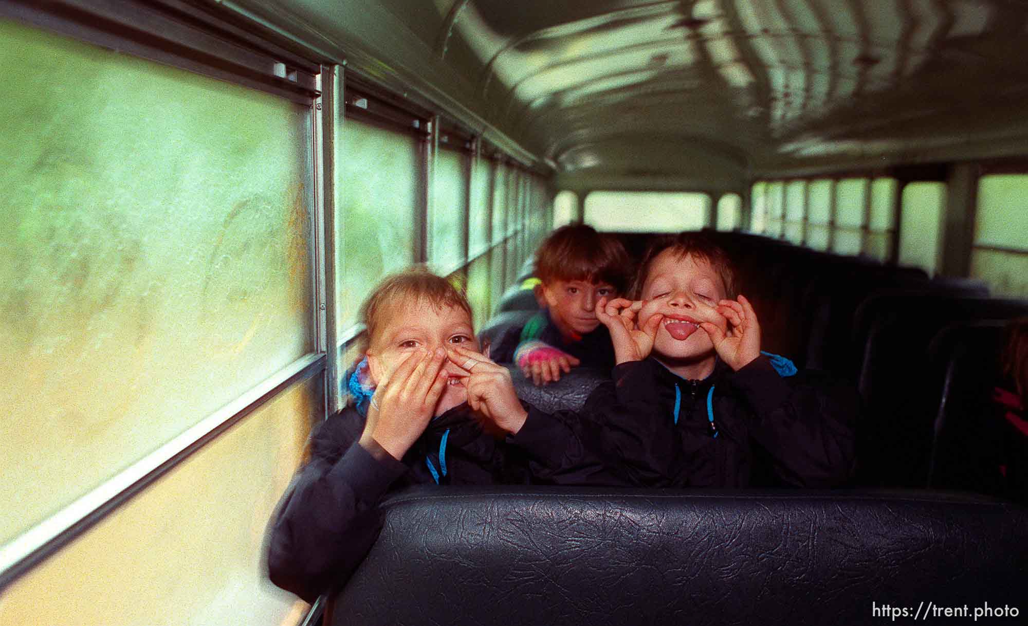 Kids making faces for the camera on school bus.