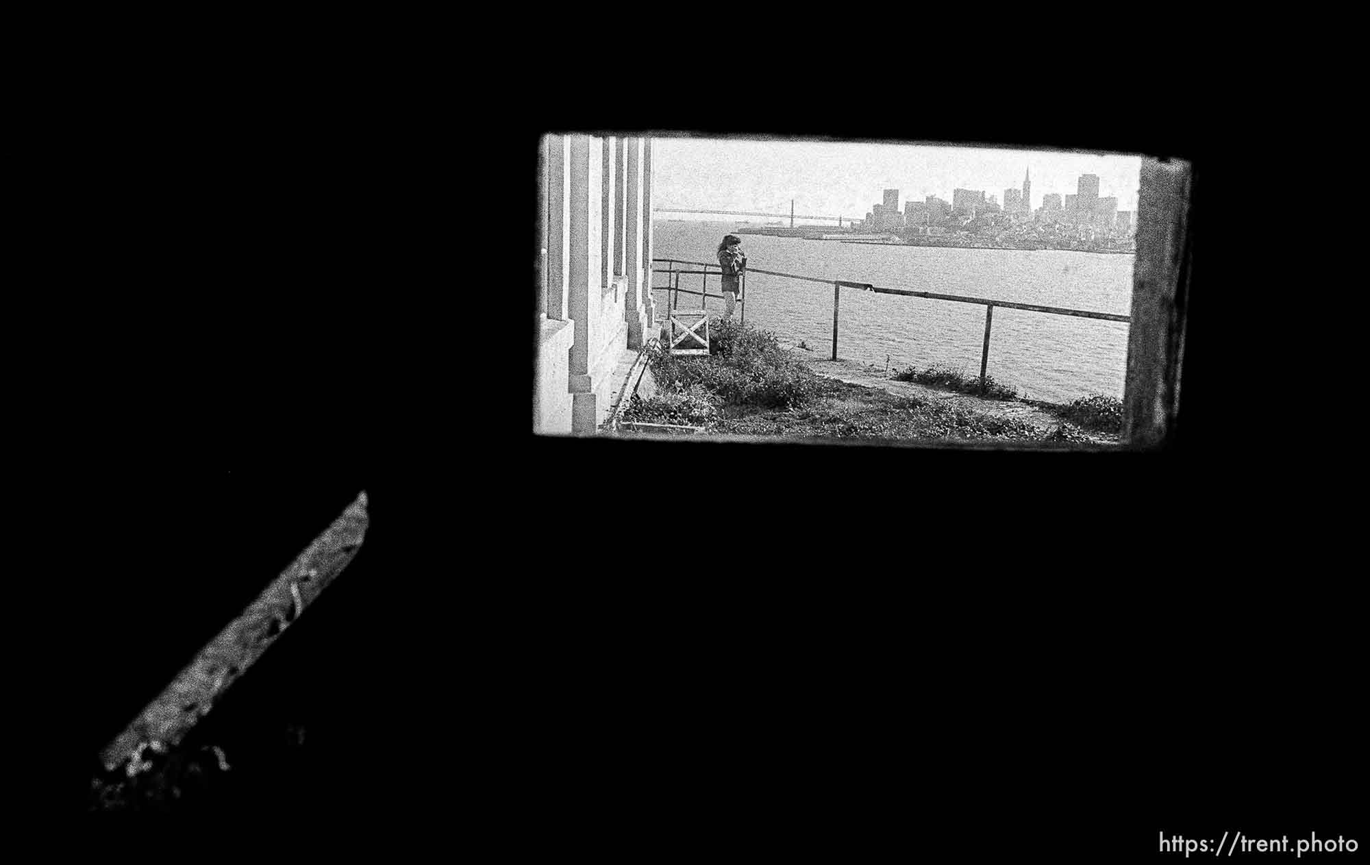 Woman and San Francisco skyline through tiny window at Alcatraz