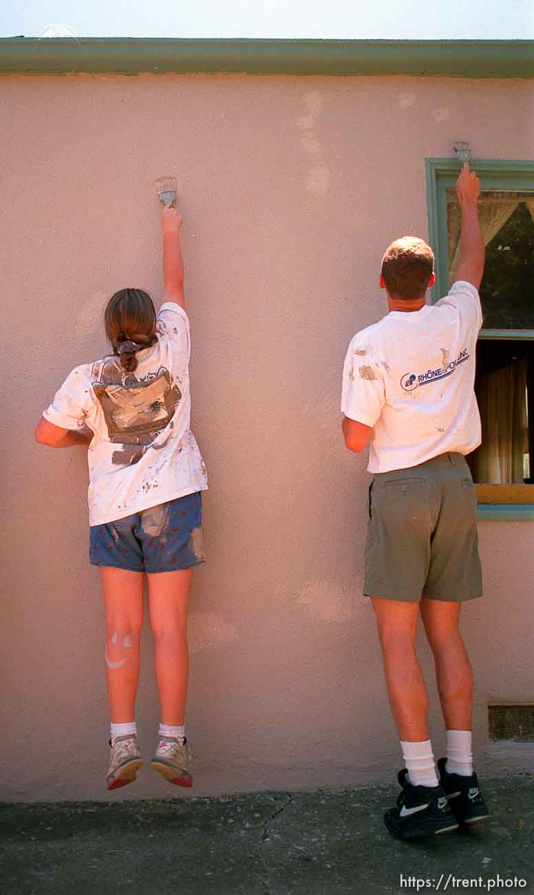 Girl jumping up while painting house