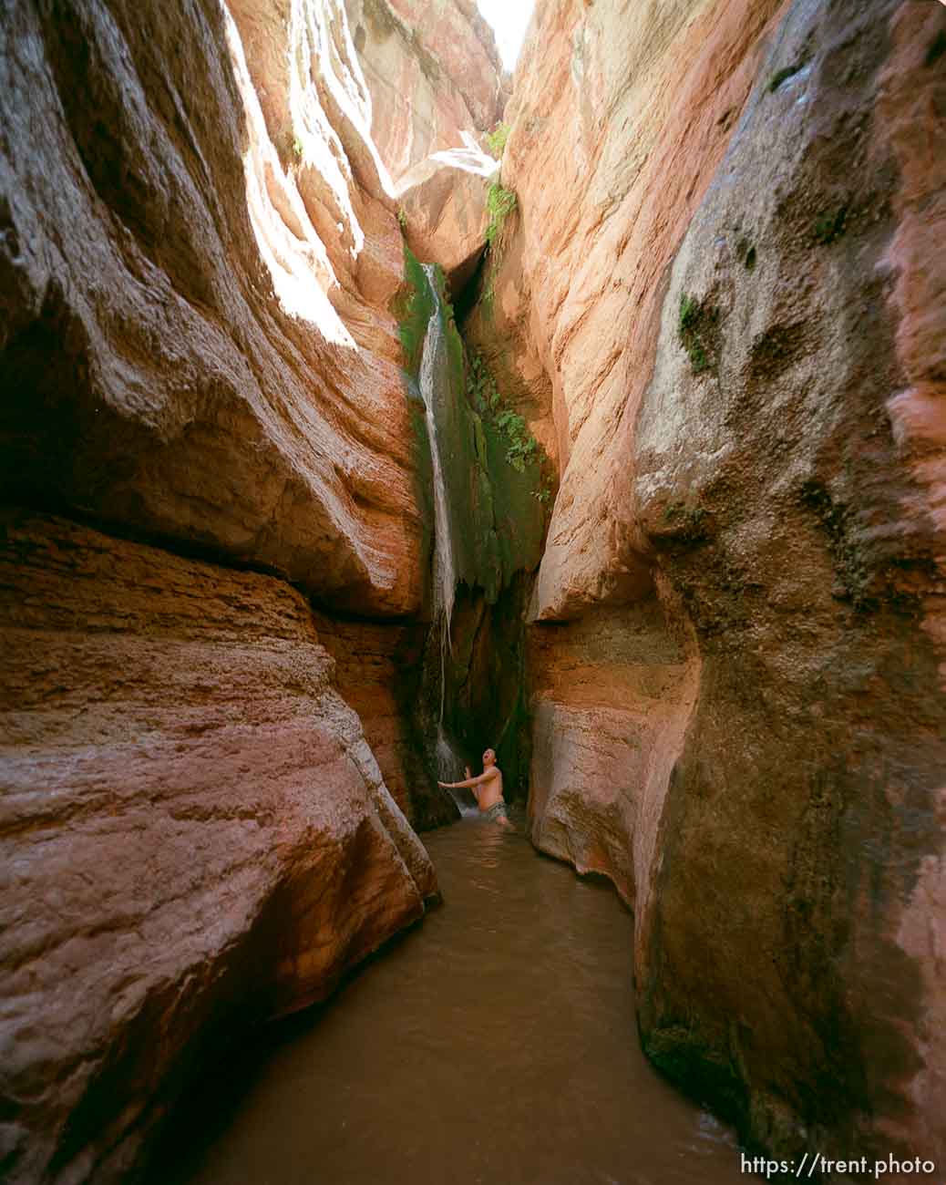 Chris Smith under slot canyon waterfall. Grand Canyon flood trip.