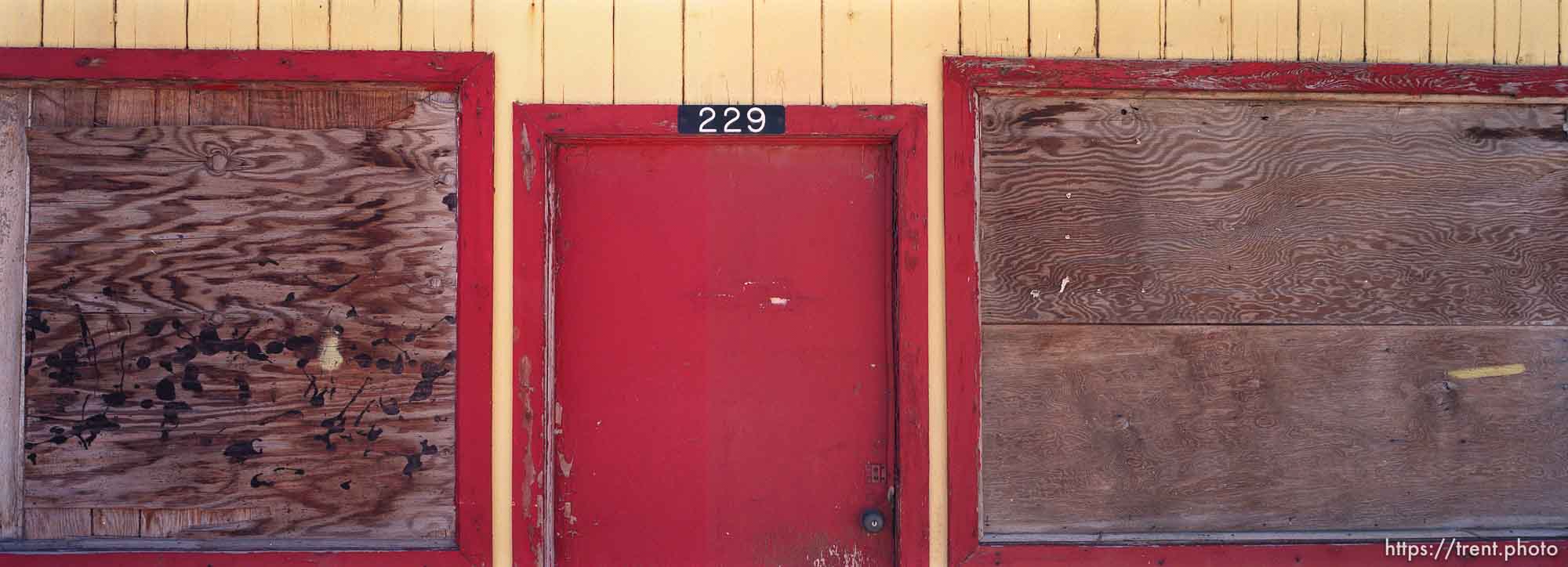 Red door and boarded up windows.