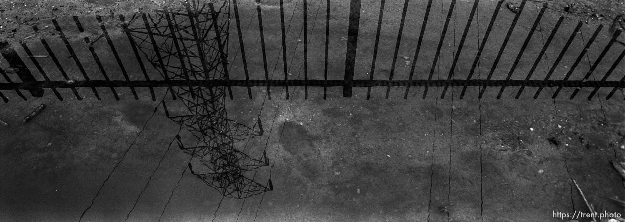 Powerline and fence reflected in water