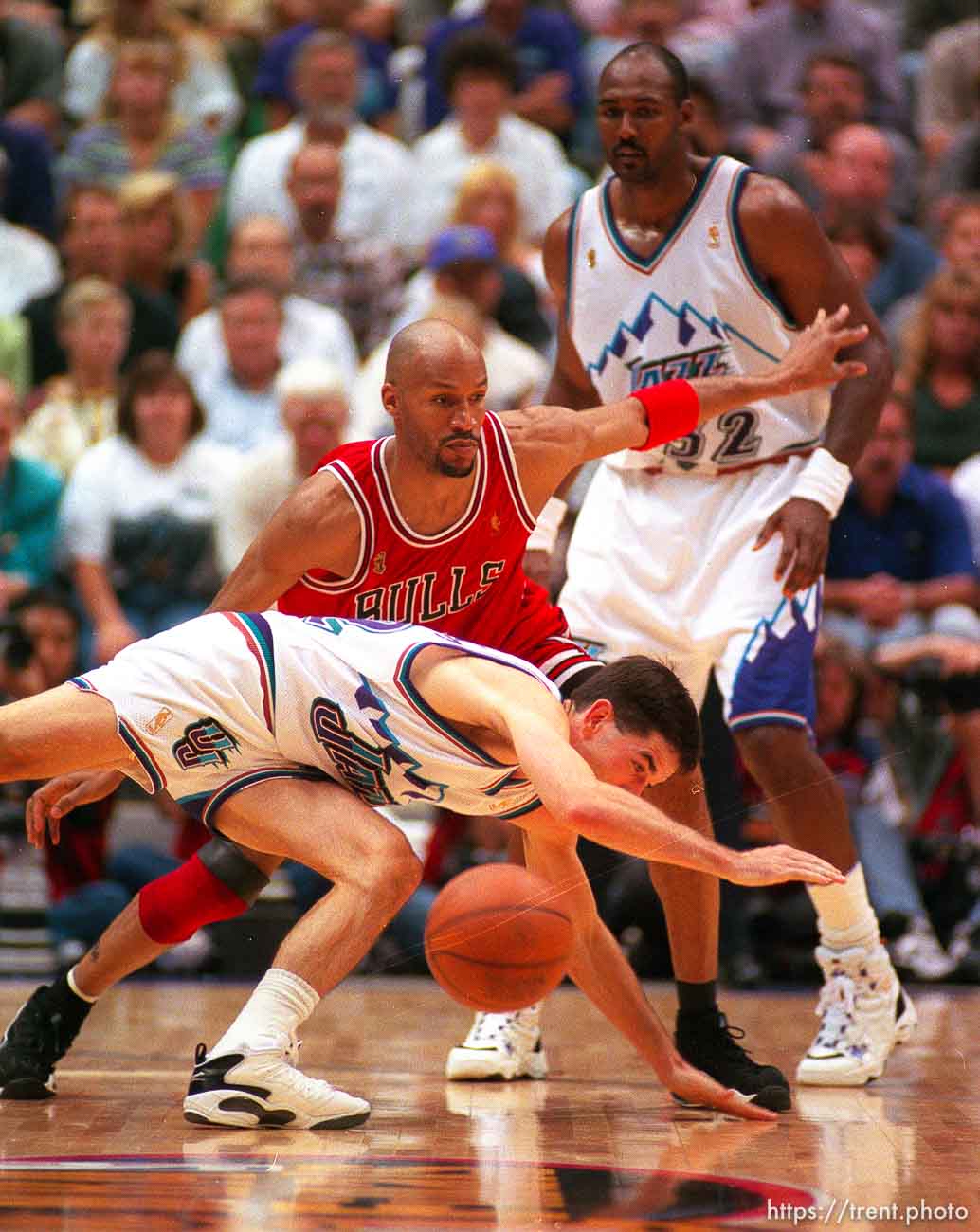 Utah's John Stockton dives to the floor with Chicago's Ron Harper defending. Karl Malone in background at the NBA Finals Game three, Utah Jazz vs Chicago Bulls.