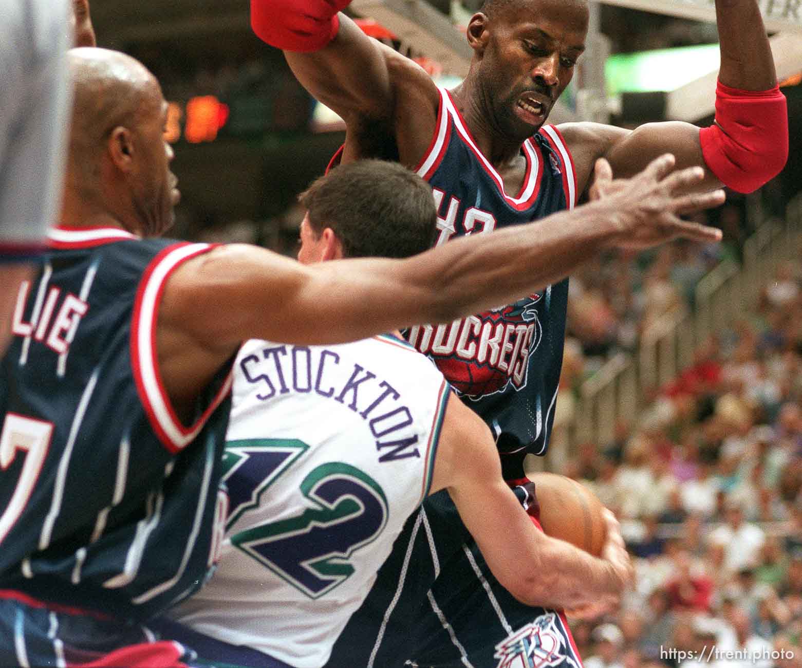 Utah's John Stockton passes around Houston's Kevin Willis (right), Mario Elie at left, at Utah Jazz vs. Houston Rockets, game 5 of the 1st round, NBA Playoffs. Jazz won.