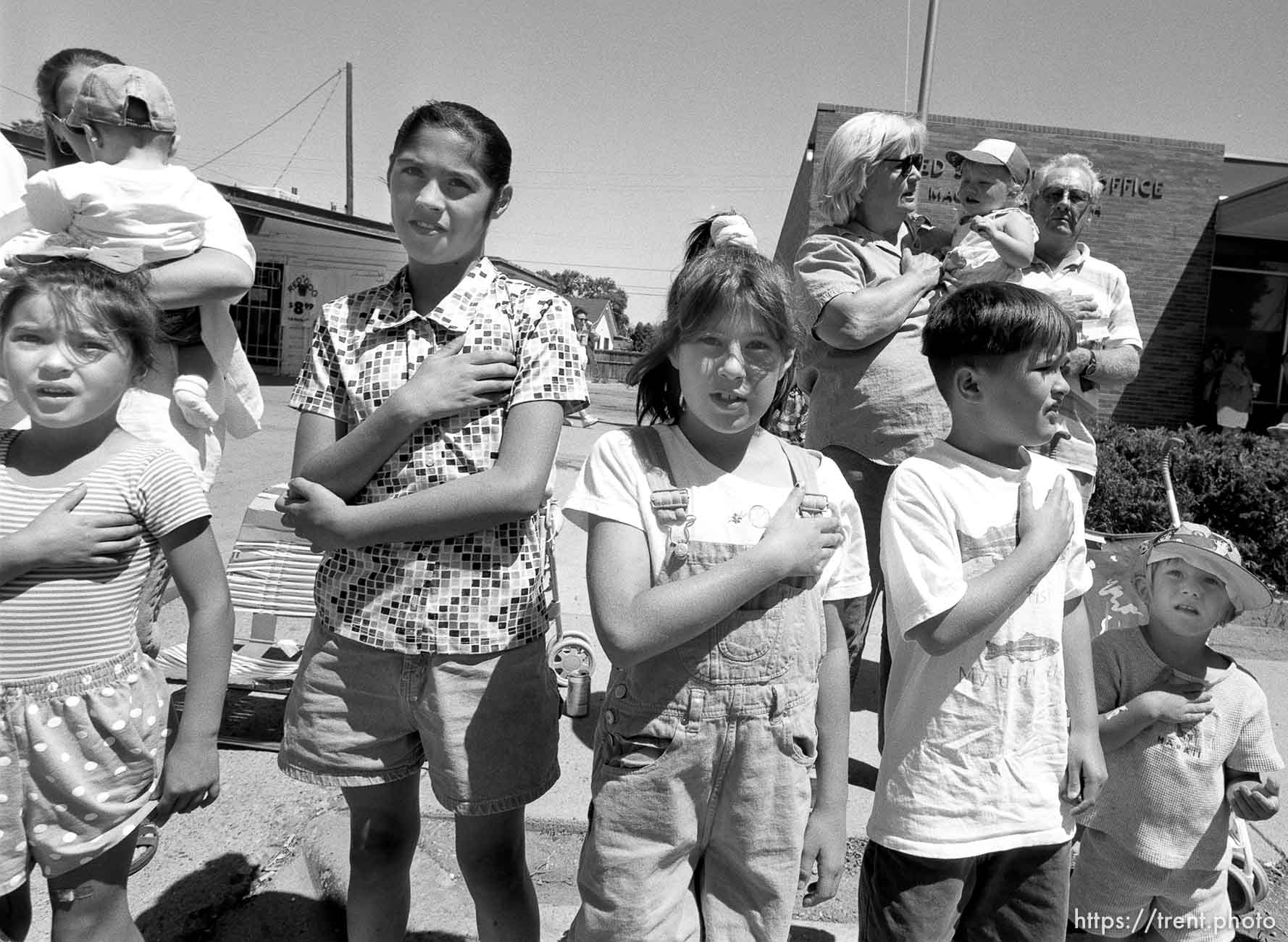 Parade watchers put their hands on their hearts as the U.S. flag passes at the 4th of July parade on Main Street.