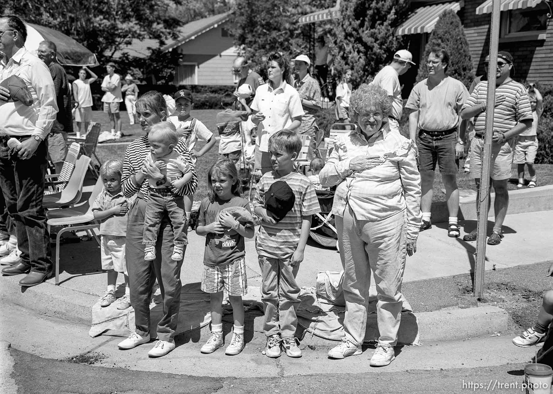 Parade watchers cover their hearts as the U.S. flag passes at the 4th of July parade on Main Street.