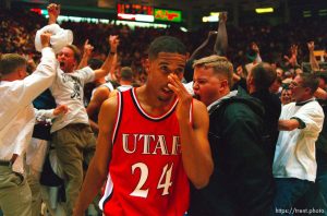 Utah's Andre Miller walks past Utah State fans celebrating their win over 9th ranked Utah at Utah vs. Utah State.