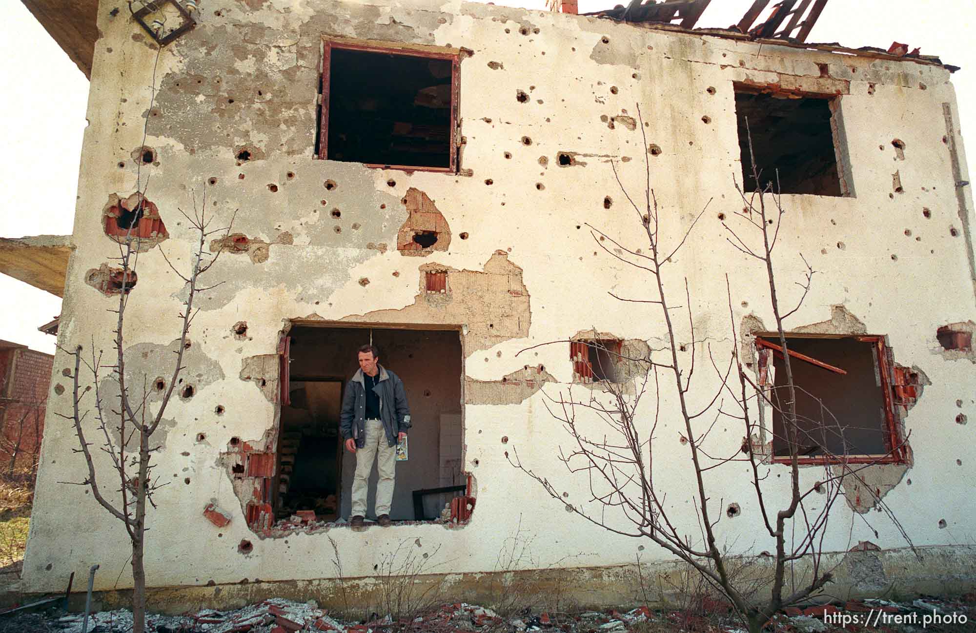 Naim Begiri in the ruins of his uncle's house, where he hid from Serb forces during the war.