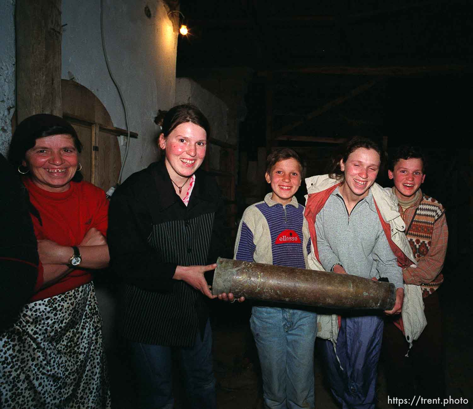 Kids holding an artillery shell casing at traditional dinner with the Hoxha family.