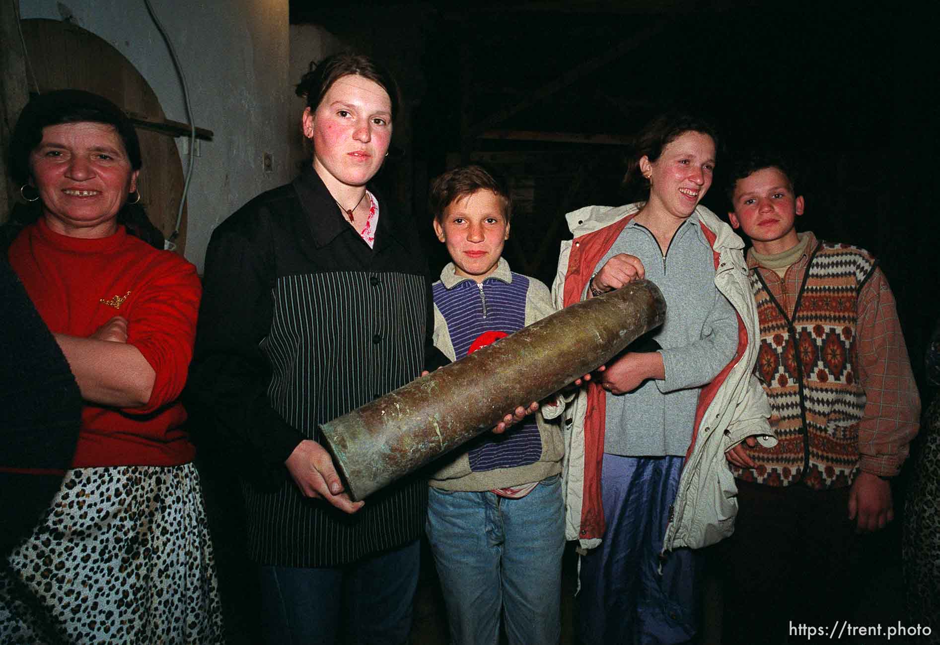 Kids holding an artillery shell casing at traditional dinner with the Hoxha family.