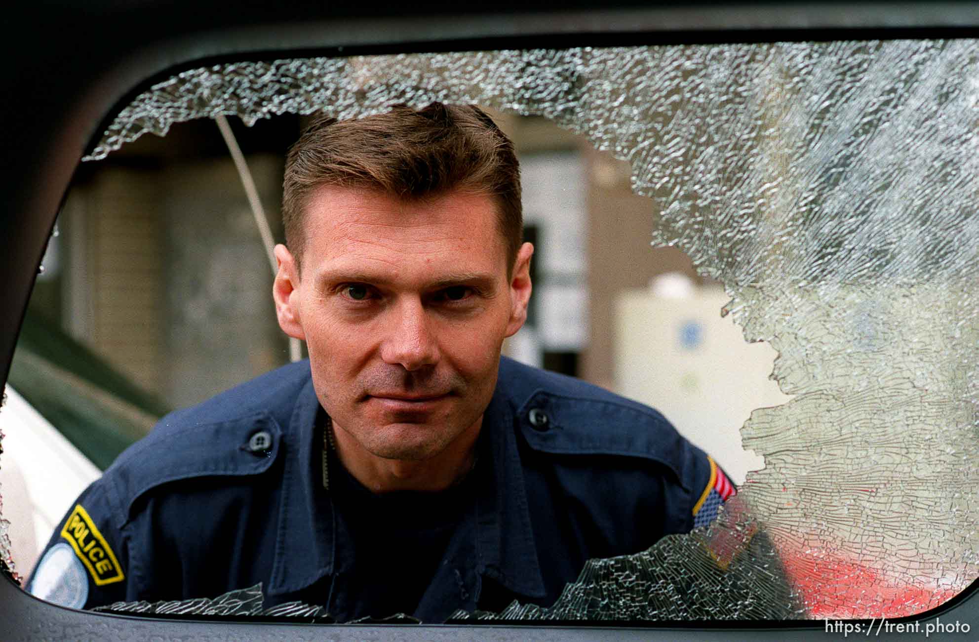 UNMIK police officer Zane Smith looking through the broken glass window on a police vehicle.