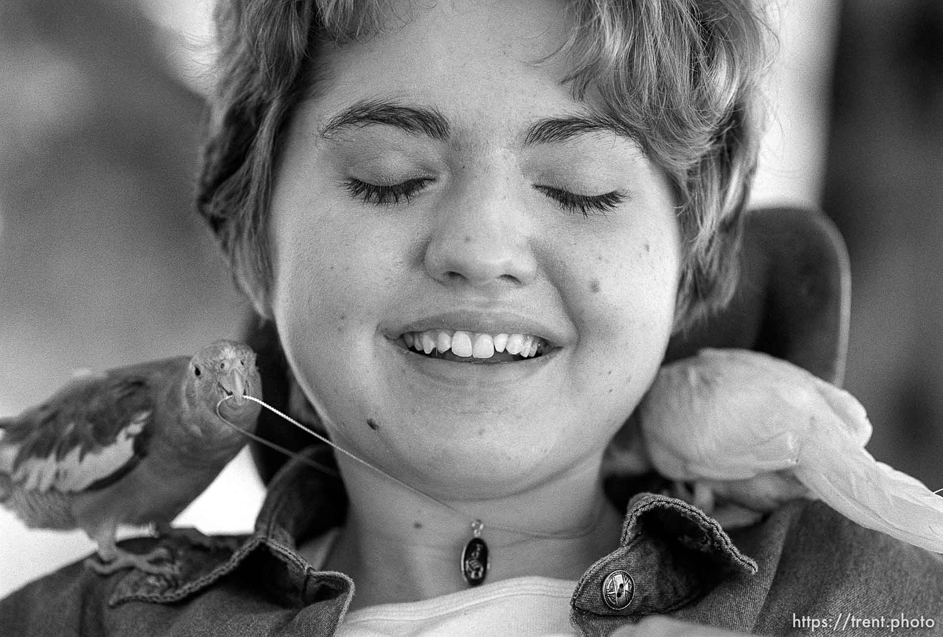 Michelle Salisbury laughs as the family's pet birds, Lady and Sonny, tug at a necklace she received for completing a number of tasks and graduating from her seminary class.