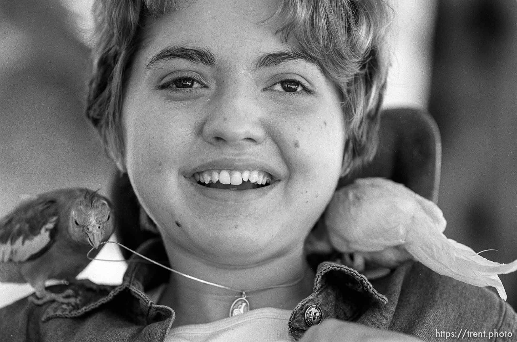 Michelle Salisbury laughs as the family's pet birds, Lady and Sonny, tug at a necklace she received for completing a number of tasks and graduating from her seminary class.