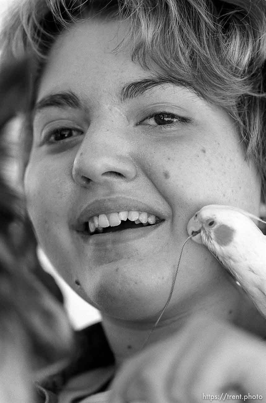 Michelle Salisbury laughs as the family's pet birds, Lady and Sonny, tug at a necklace she received for completing a number of tasks and graduating from her seminary class.