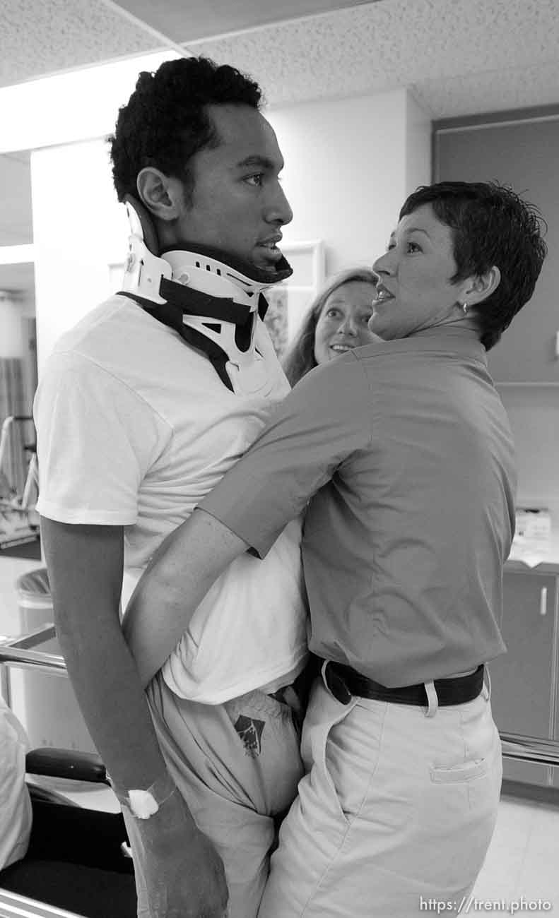 During a physical therapy session with Misti Timpson (right) and Nikki Conrad (center), Una Taufa briefly stands upright under his own power for the first time since his spinal injury. West High football player Una Taufa suffered a severe neck injury in a game two weeks ago and is partially paralyzed. He has begun the long and arduous rehabilitation process at LDS Hospital.
. 09/27/2001, 10:59:06 AM