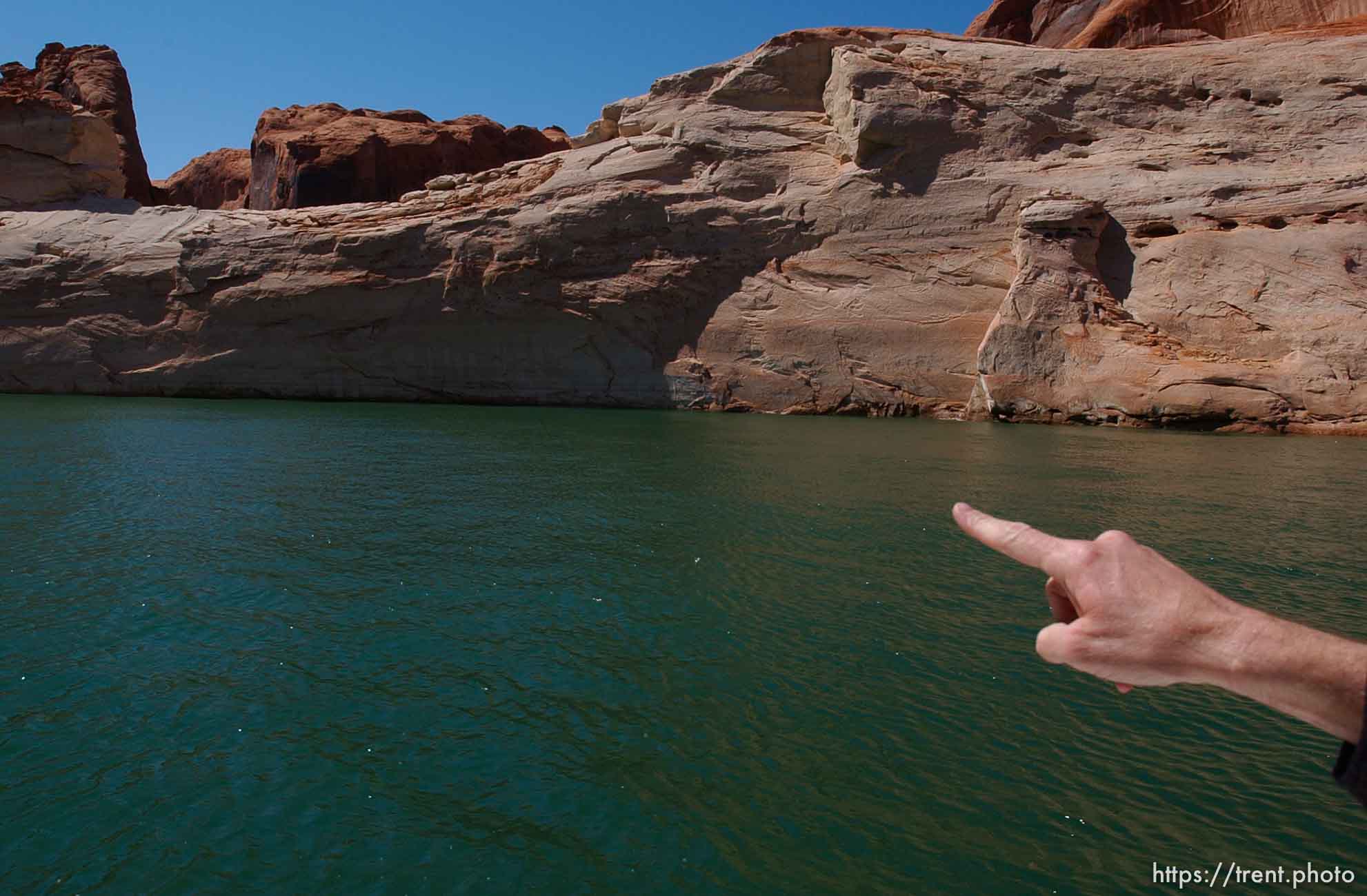 Richard Ingebretsen, founder and president of the Glen Canyon Institute, points out the top of the previously submerged Gregory Natural Bridge. He believes that if the lake drops another five feet, the arch will be above the lake's surface. Landmarks which had previously been submerged in Glen Canyon are now becoming visible with the lower water levels in Lake Powell.