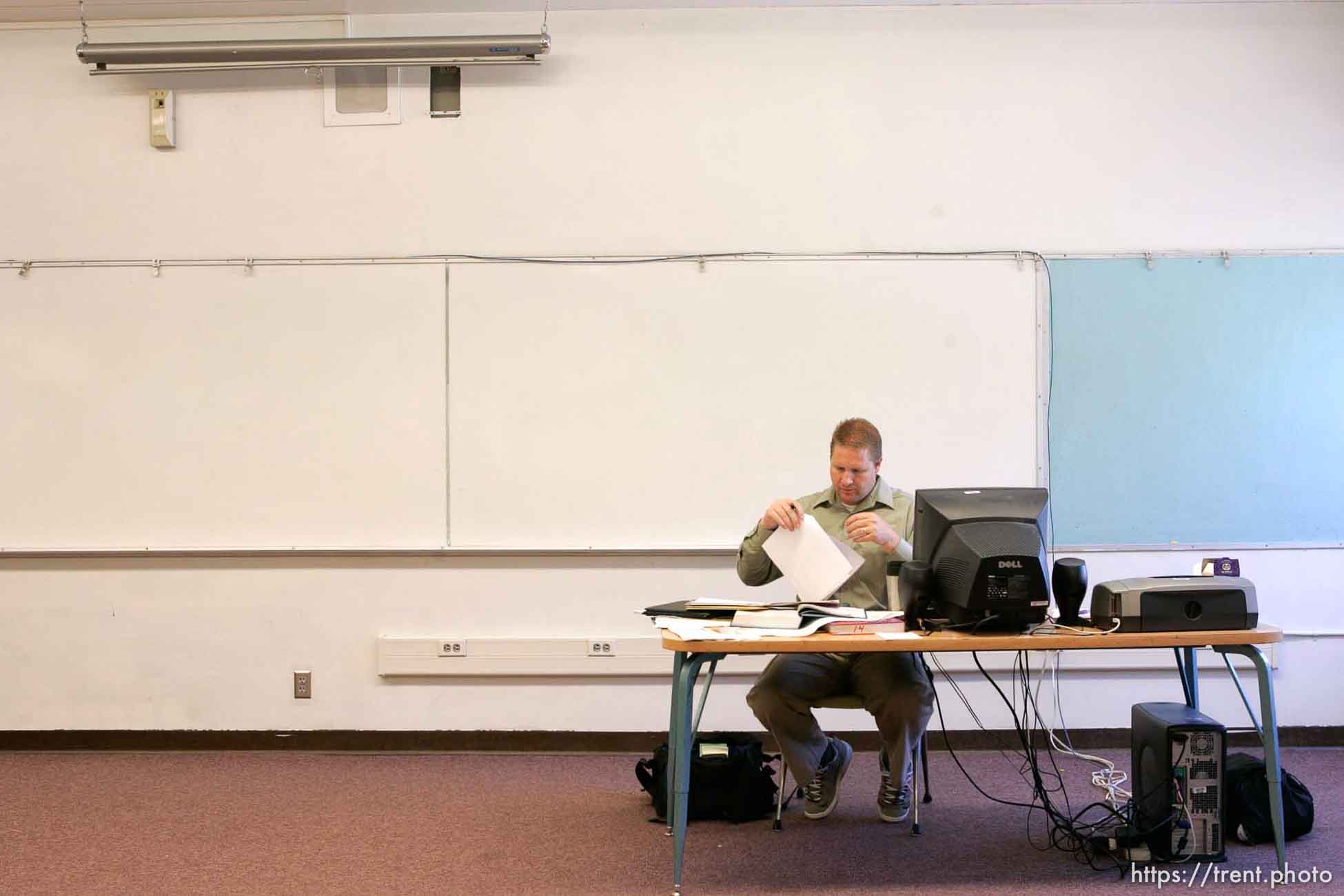 East Carbon High School math teacher Rex Jepson sifting through papers in his empty classroom. The small town of Sunnyside's East Carbon High School is being closed. The students will be transfered to Price's Carbon High School, a 25-minute bus ride away.