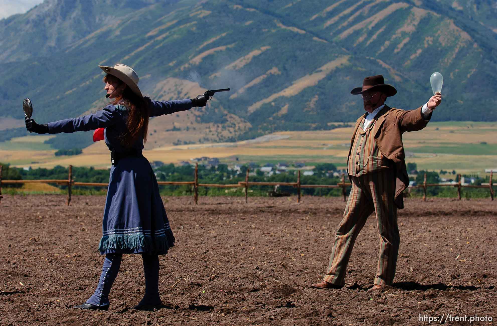 Famous western sharpshooter Annie Oakley (Marna Jean) uses a mirror to take aim at a balloon in her partner Frank Butler (Doug Davis)'s mouth during a Wild West Show that kicked off the Festival of the American West at Wellsville's American West Heritage Center.