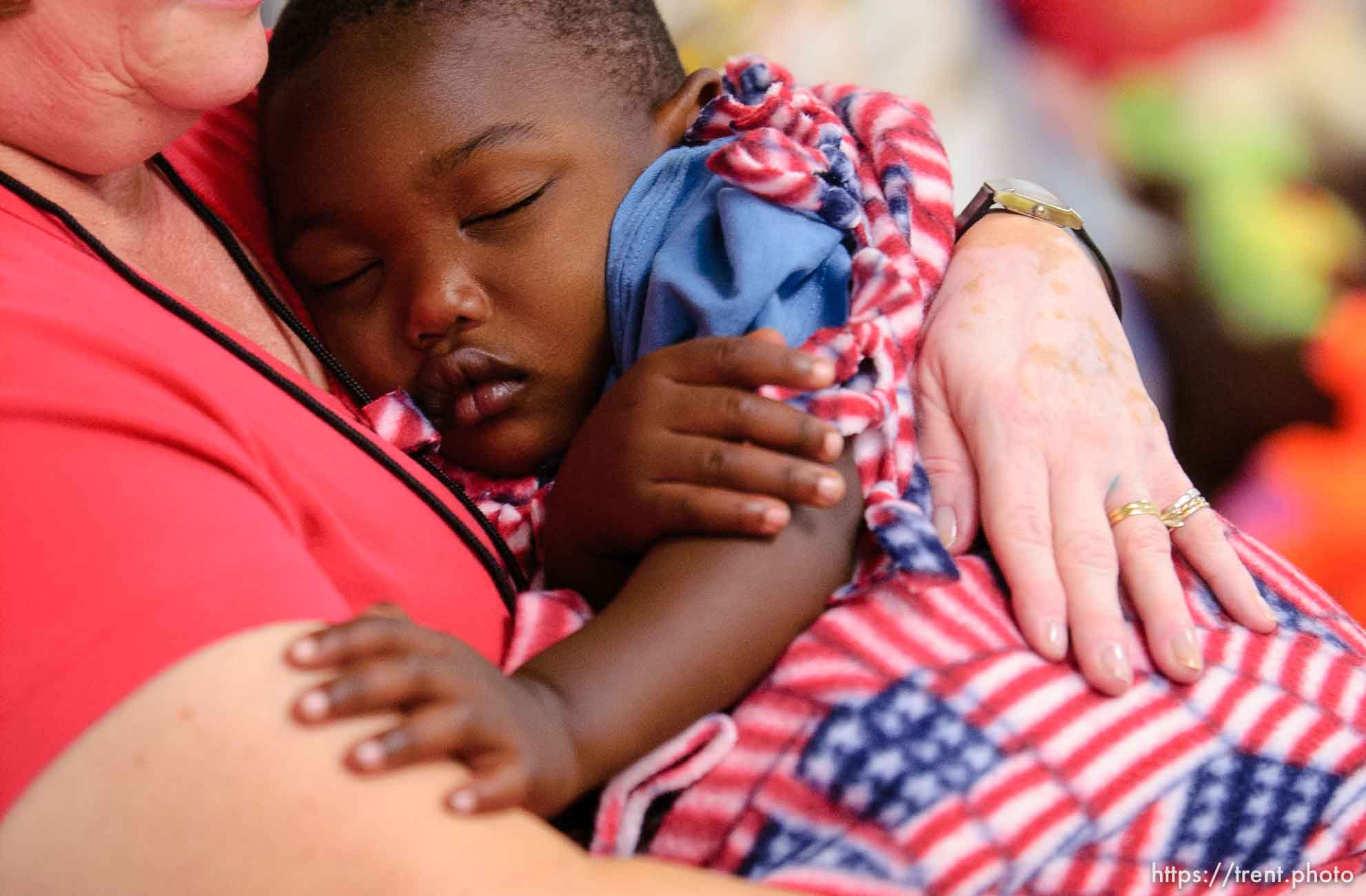 children taking naps in volunteers' arms in day care center at Camp Williams, where people who were evacuated from the hurricane Katrina disaster in New Orleans, are making a go of it.