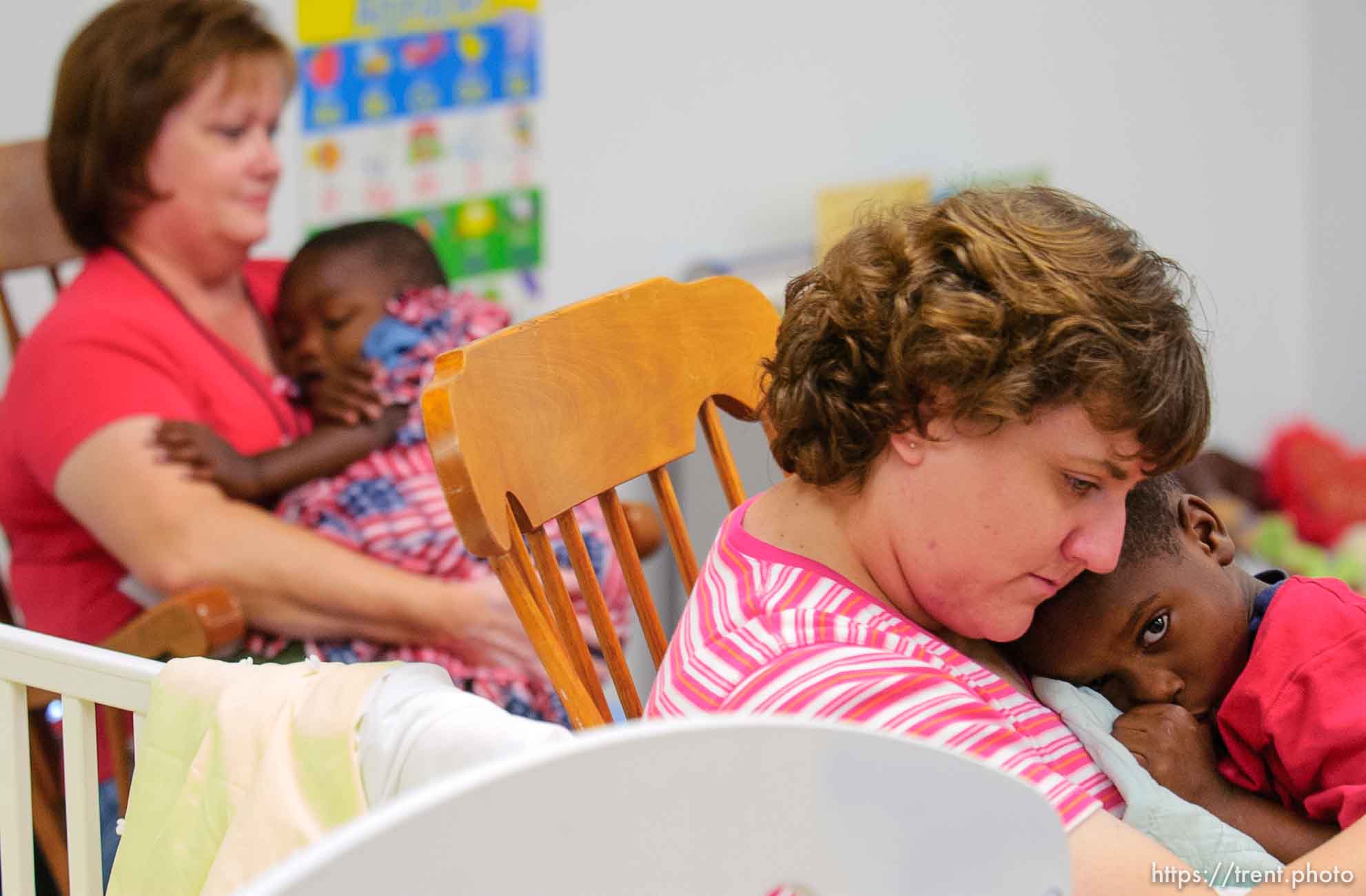 Children find solace at nap time in the arms of volunteers Kathy Jensen (left) and Carolyn Clark (center) in the daycare center (Camp BeBe) at Camp Williams, where people who were evacuated from the hurricane Katrina disaster in New Orleans, are making a go of it.