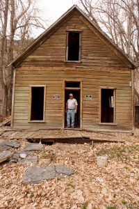 Ophir - Ophir Mayor Walt Shubert and others are working to restore historic homes in this small scenic town. Shubert is pictured standing in the doorway of the historic Alt home, which was moved to Ophir from Mercur in 1930.