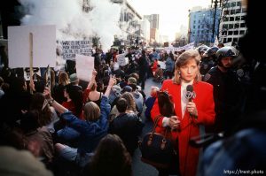 Television reporter in the middle of sit-down protest on Market Street at Gulf War protest.